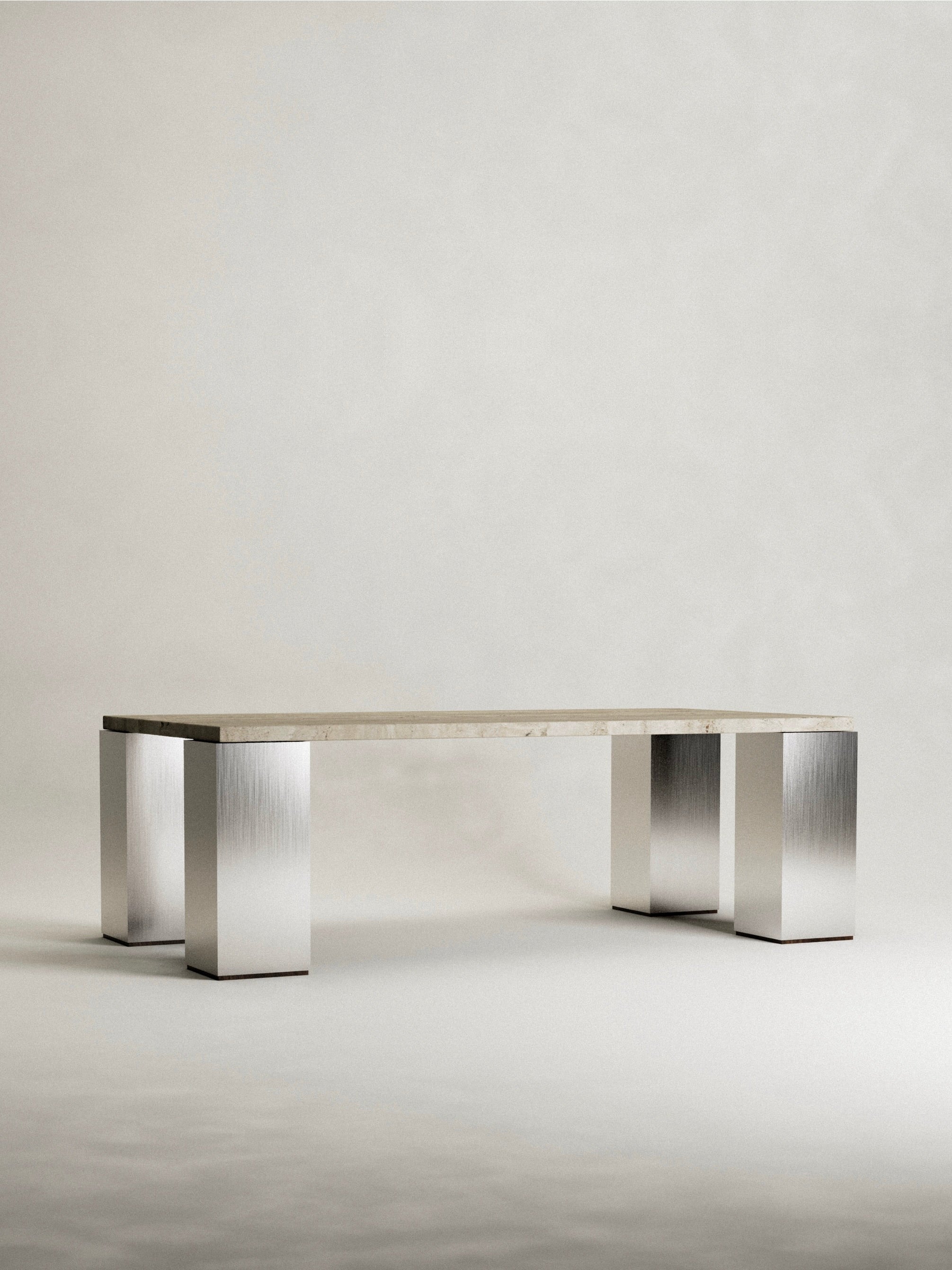 The 'Fragua' Dining Table by Siete Studio features a rectangular beige top and four metallic legs. This modern, minimalist piece highlights metallurgical craftsmanship with brushed metal textures on the legs, set against a plain design backdrop.