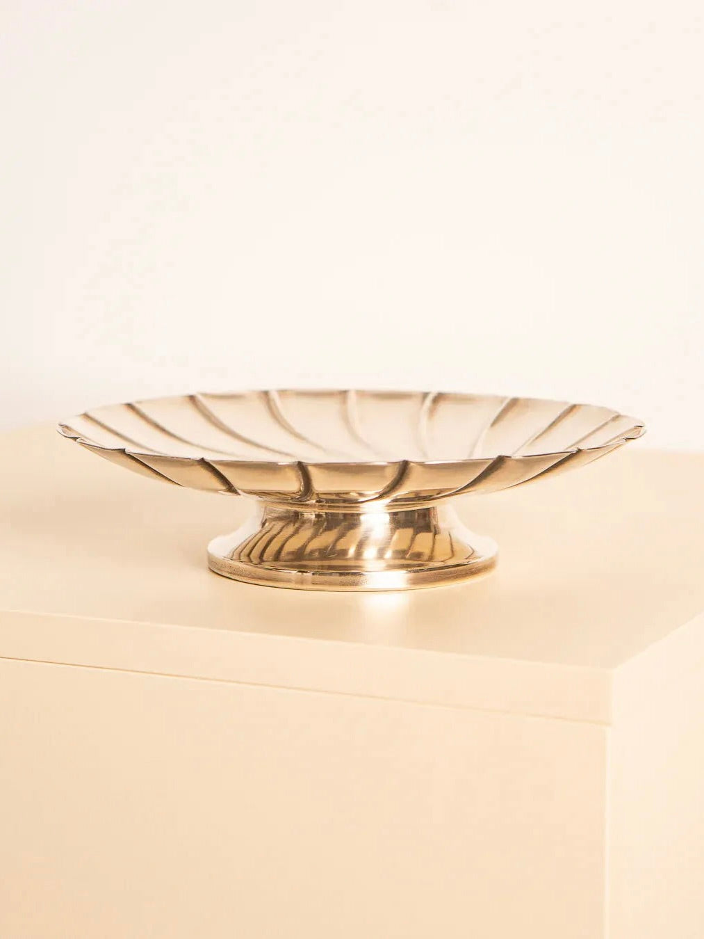 A silver-plated bowl from Treaptyque, reminiscent of the 60s, sits stylishly on a light-colored surface against a plain background. Its shiny finish adds timeless elegance and a hint of retro charm to the minimalist setting.