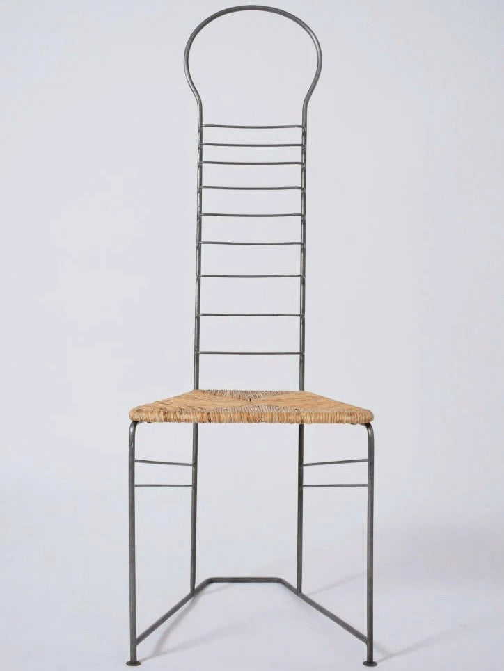 The Pair of Iron and Straw Chairs from the 1980s by Barracuda Interiors showcases a tall, minimalist design with a high, circular backrest crafted from slender metal rods, complemented by a woven straw seat. The tubular iron frame provides a sleek and open look, reflecting the modern artistic aesthetics reminiscent of chairs from the 1980s.