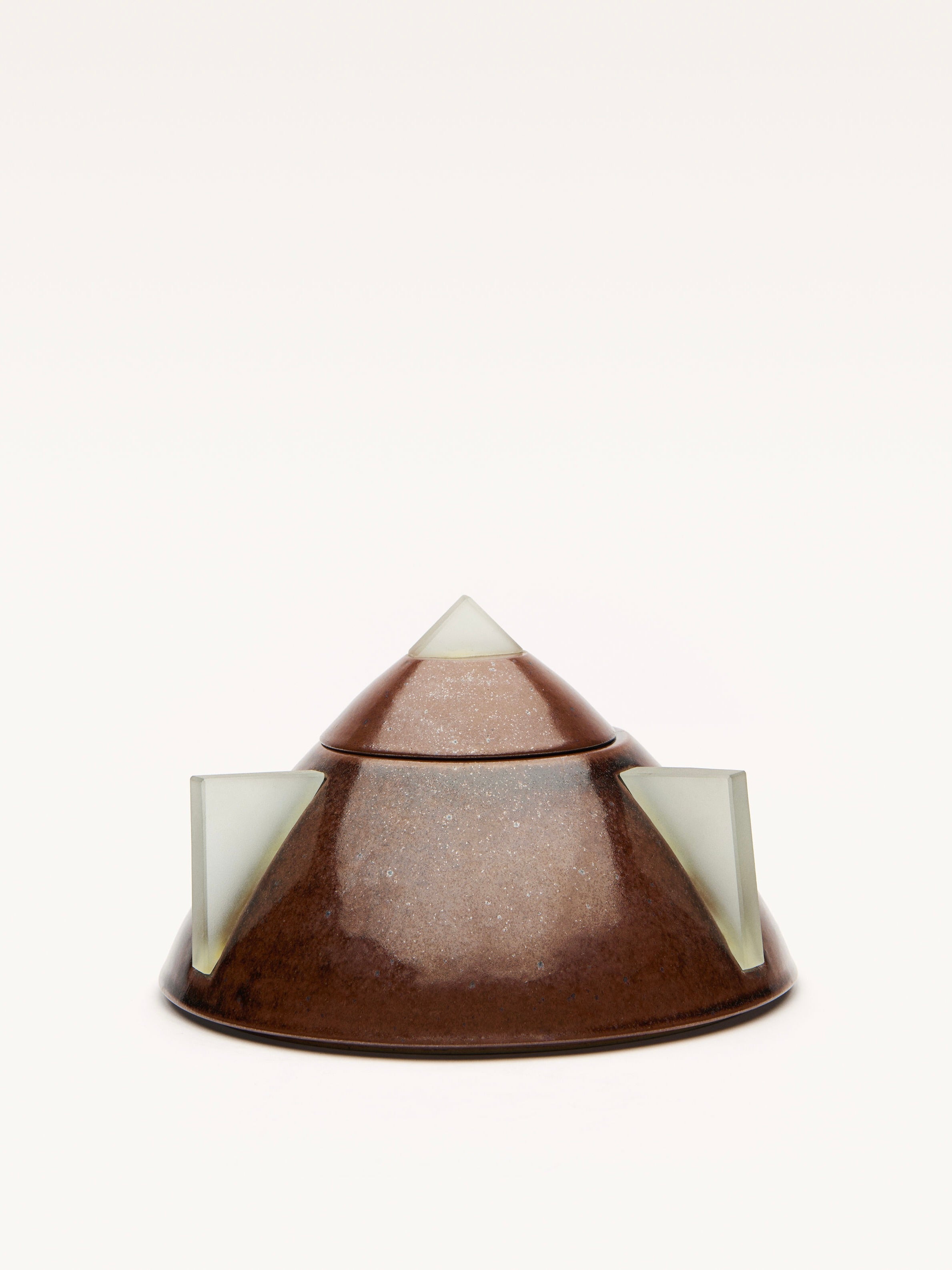 A round, brown ceramic bowl by Galerie MLS has a glossy surface and pyramid-like top in art deco style. It features three triangular, light-colored protrusions resembling glass spikes, evenly spaced at its base against a plain white background.