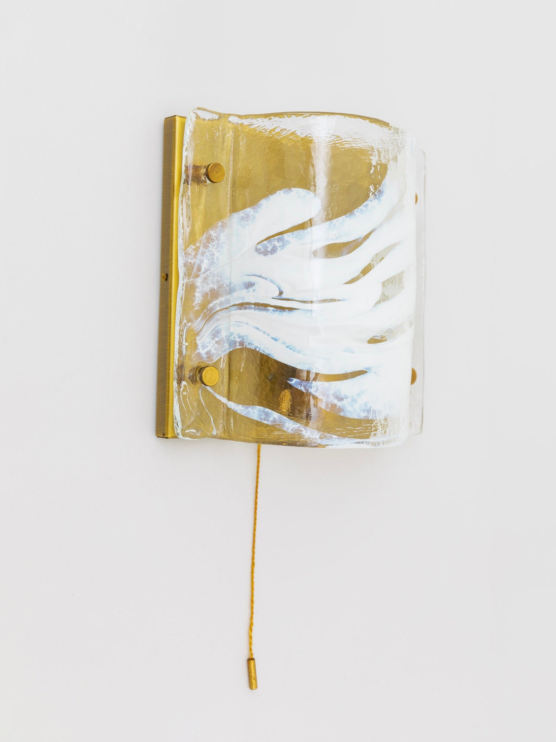 The Bottega Jacobs J.T. Kalmar Murano Wall Lamp 60s features a vintage curved glass shade with wavy white patterns, elegantly secured by gilded brass fittings. A gold pull chain enhances its timeless charm against the plain white wall.