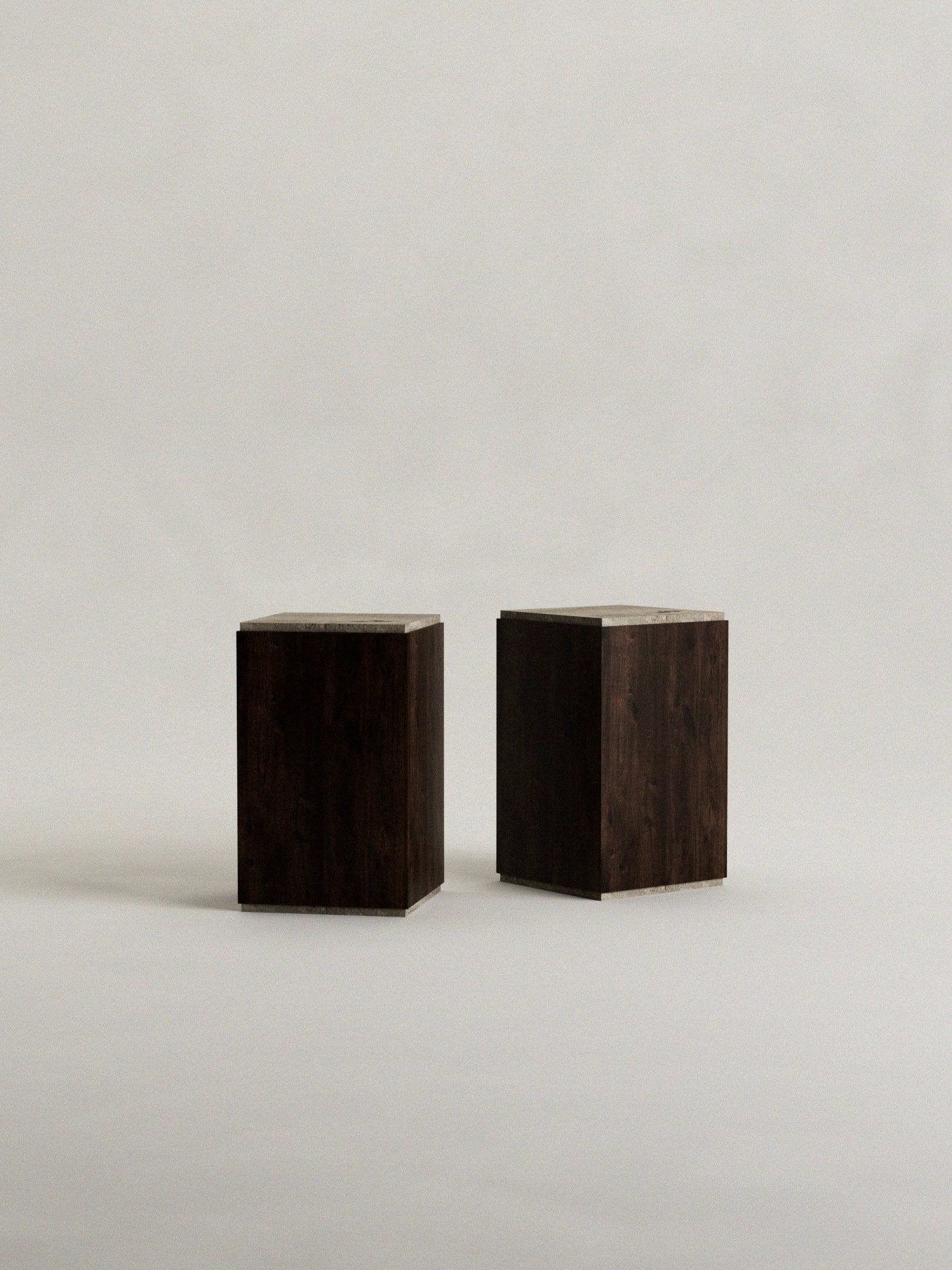 Two dark wooden cubes rest on a handcrafted 'Calakmul' plinth by Siete Studio, set against a light background. Positioned side by side, they cast gentle shadows below, emphasizing their solid walnut construction.