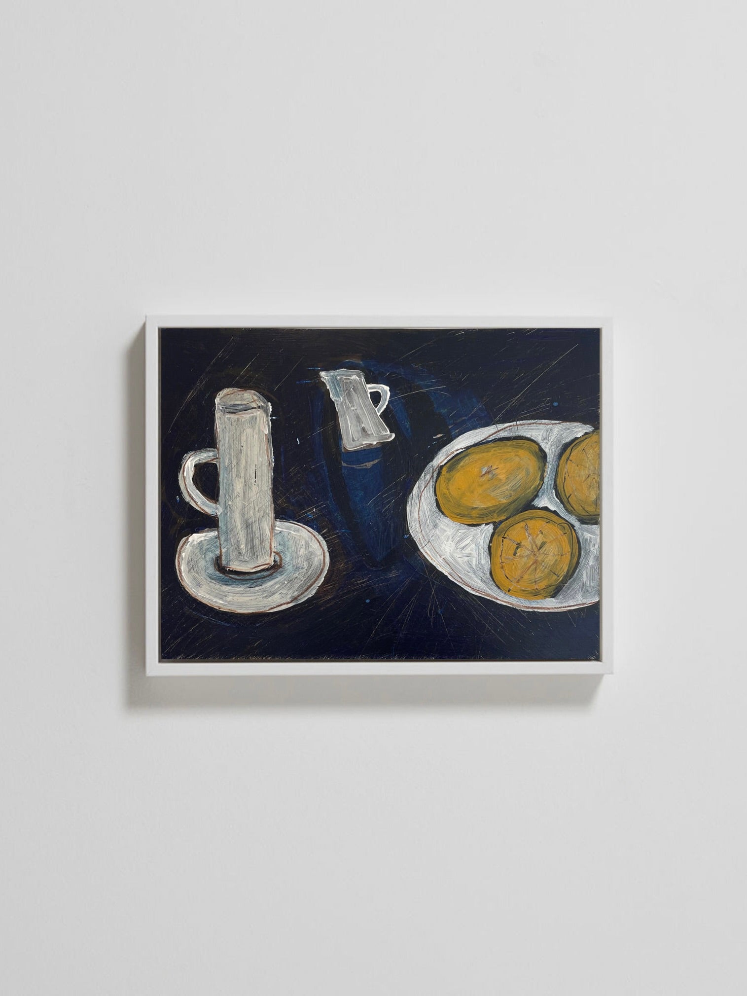 A framed still life painting titled "Three Lemons" by Lara Voce hangs on the wall, featuring a minimalist composition with a glass and pitcher on one side and three round bread rolls on a plate, set against a dark background.