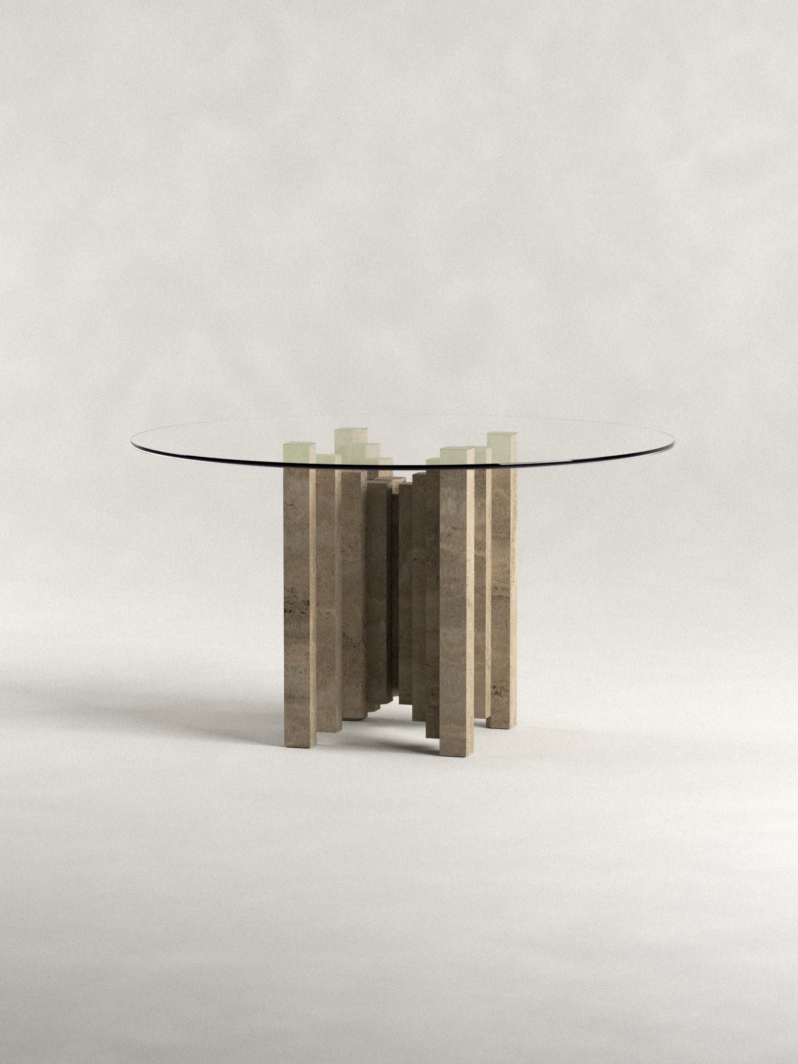 The 'Calakmul' Dining Table S2 by Siete Studio features a modern round glass top supported by a unique travertine base with handcrafted stone pillars arranged circularly. The background is a neutral, light gray, enhancing its elegant design.
