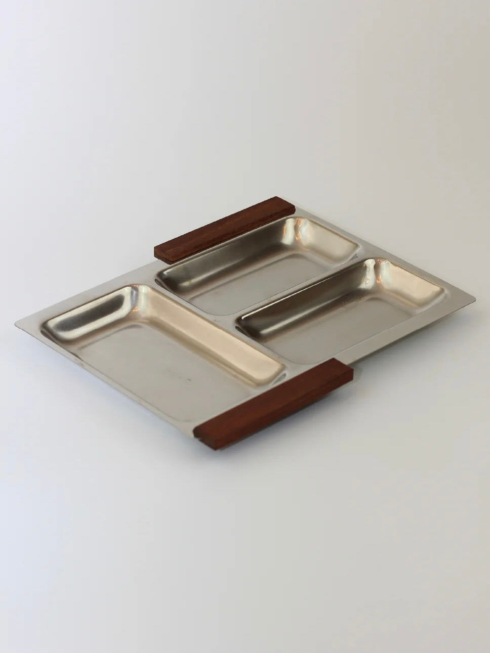 The Boga Avante Shop's Stainless Steel Danish Tray 70s is a rectangular snack tray from the 1970s, featuring two compartments and teak wooden handles on each side, elegantly set against a neutral background.