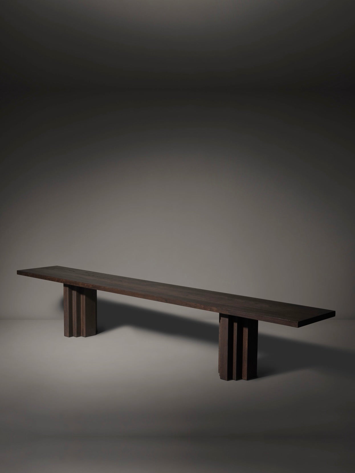 Introducing Mokko's Brut Slim Bench, a minimalist European oak piece with a dark wooden design featuring a long rectangular seat and block-style legs, creating a dramatic ambiance within the Brut collection.