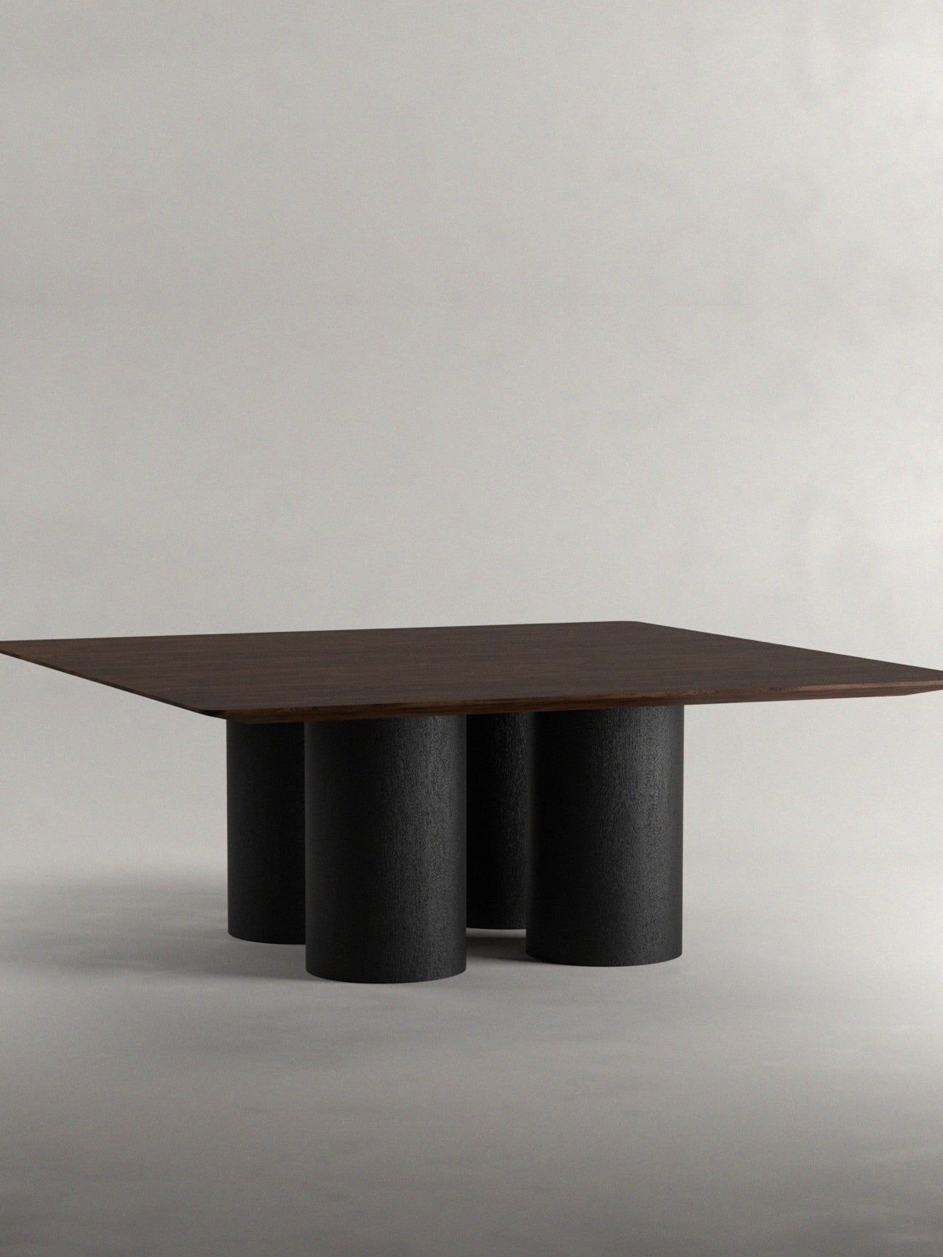 The 'Pier' Dining Table by Siete Studio features a contemporary square walnut tabletop on cylindrical black legs, set against a simple light gray background.
