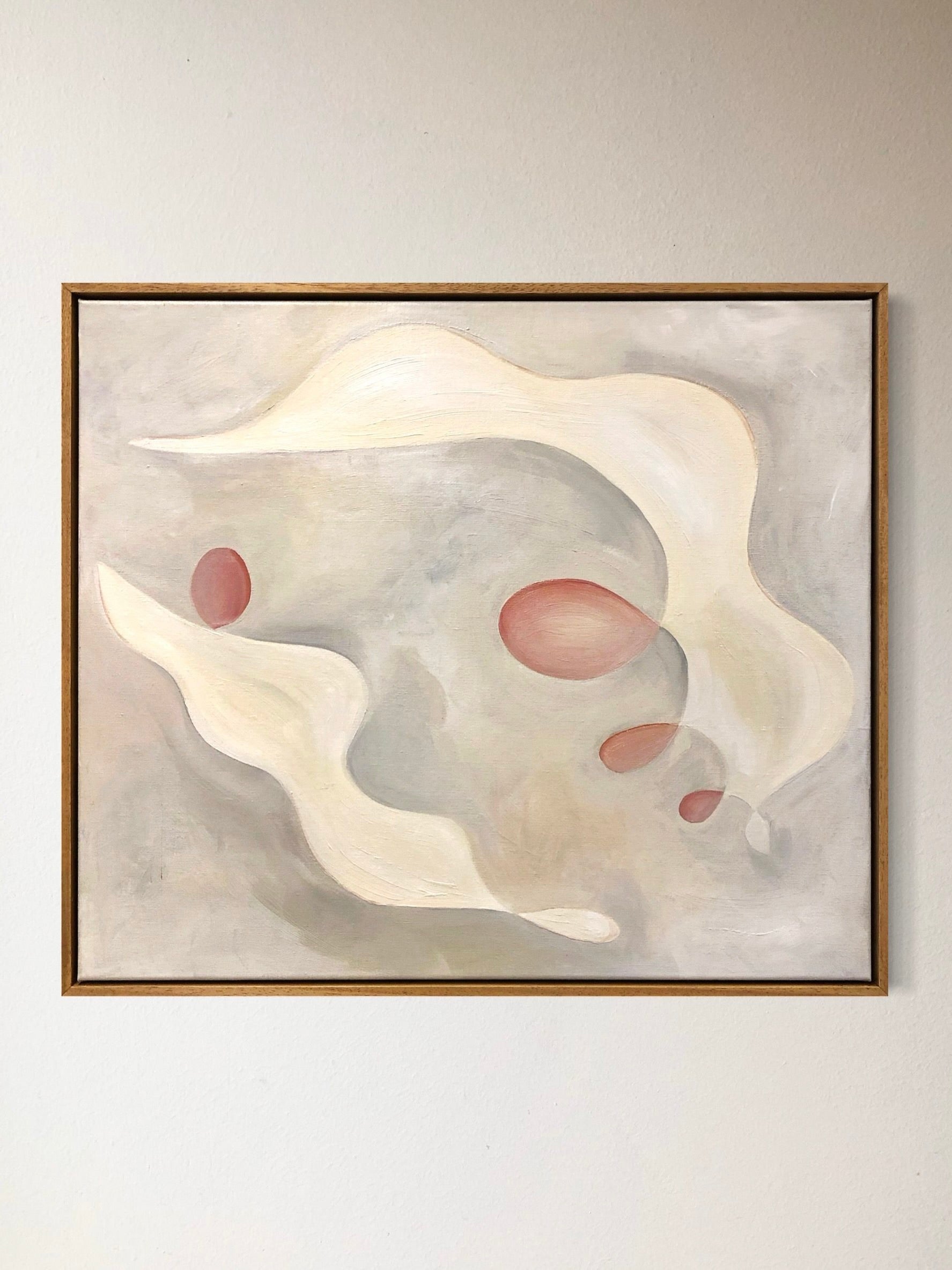 The "Tracing Light, 2024" painting by Cate Adriana features flowing cream-colored shapes and reddish ovals set against a soft gray background. Framed with a thin wooden border, this acrylic artwork beautifully conveys a sense of movement and calmness, akin to tracing light through serene pastels.