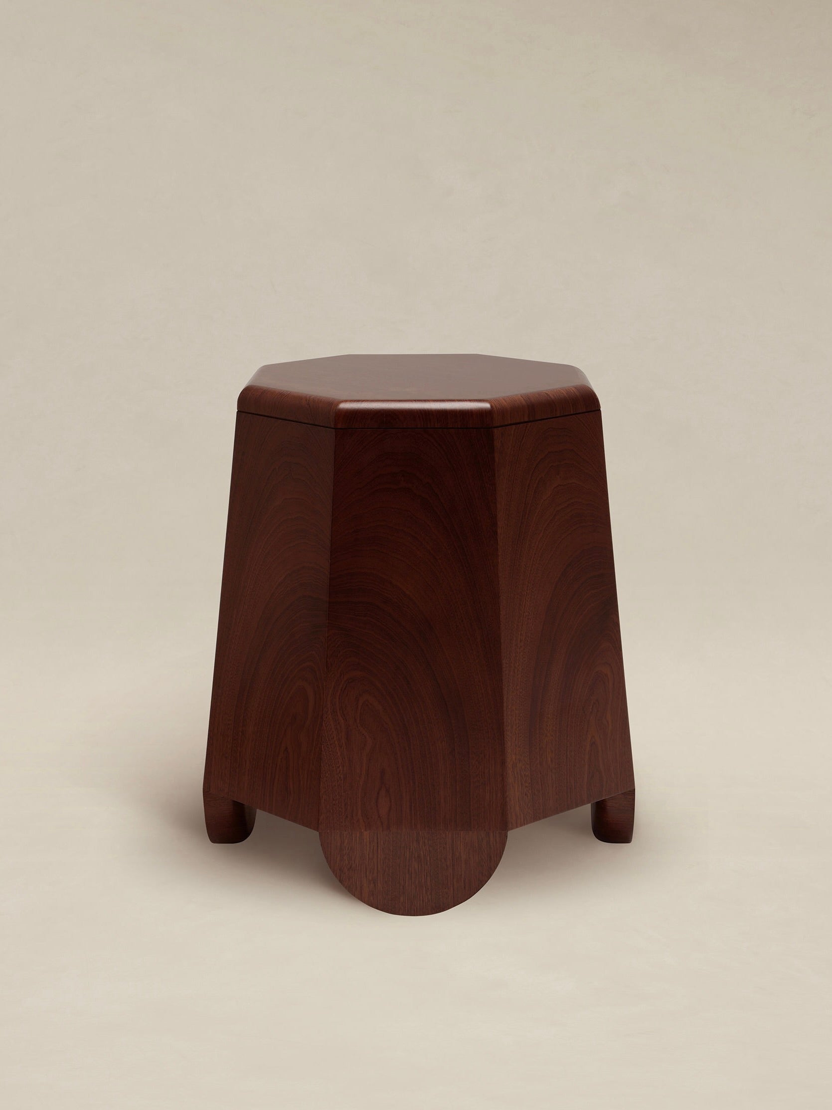 AÈDE Studios presents the Chatior Side Table, featuring a polished wooden design with an octagonal top and gently curved legs. The rich dark brown finish accentuates the natural grain patterns, evoking a sense of Byzantine architecture, while standing gracefully against a plain, light beige background.