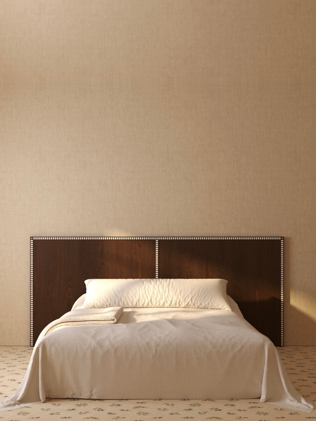A minimalist bedroom features a neatly made bed with white linens and Lemon's "Aquarama" Headboard in Chocolate Ash against a plain beige wall. A folded towel lies at the foot of the bed, and the carpet has a subtle floral pattern. Warm light softly illuminates luxury materials throughout the serene space.