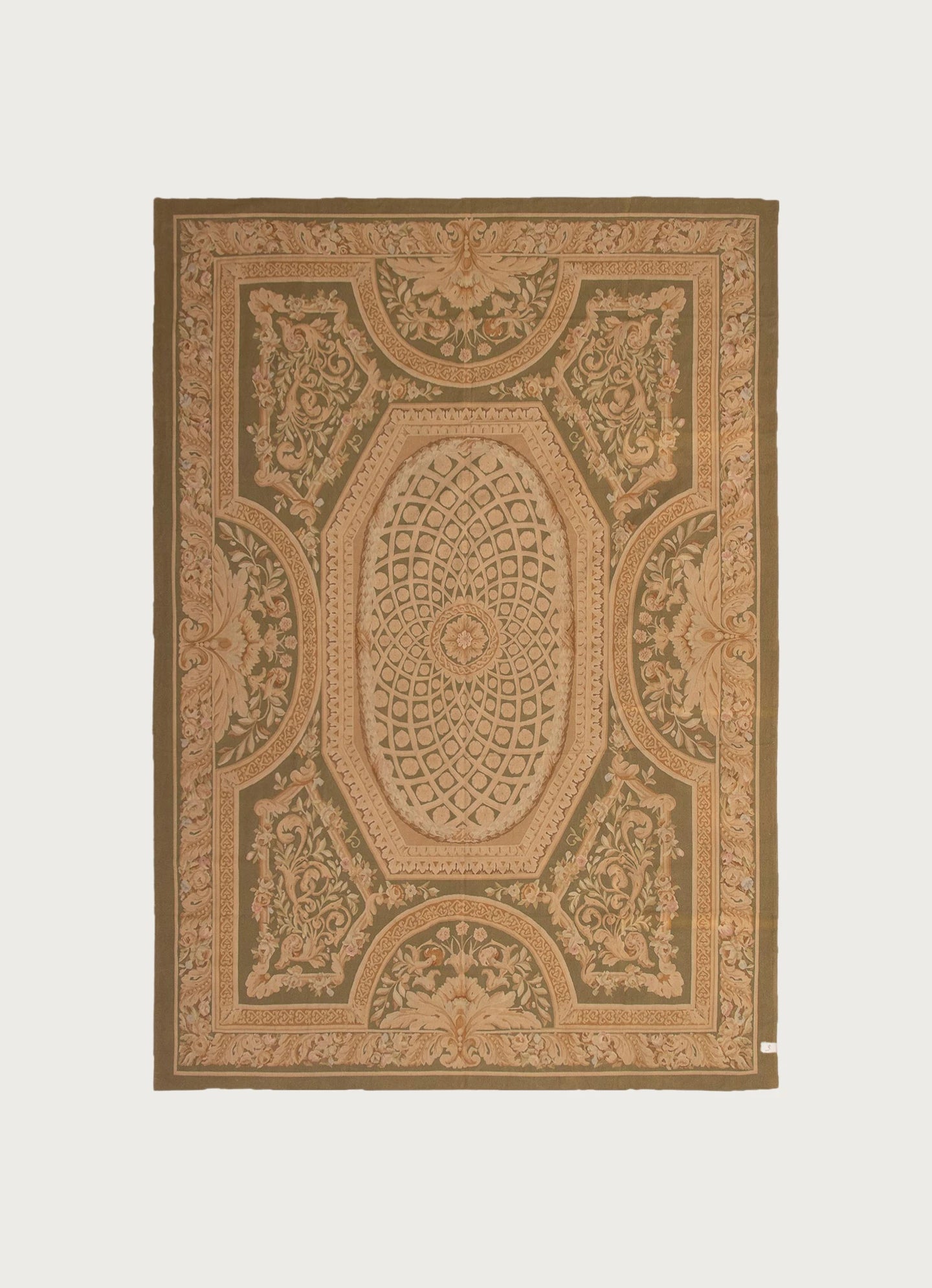 The Tapestry Rug in 'Song' by catalog:three (287 x 419 cm) features an ornate, symmetrical pattern in beige, olive green, and tan with a central oval medallion, floral motifs, and decorative borders inspired by Aubusson design.