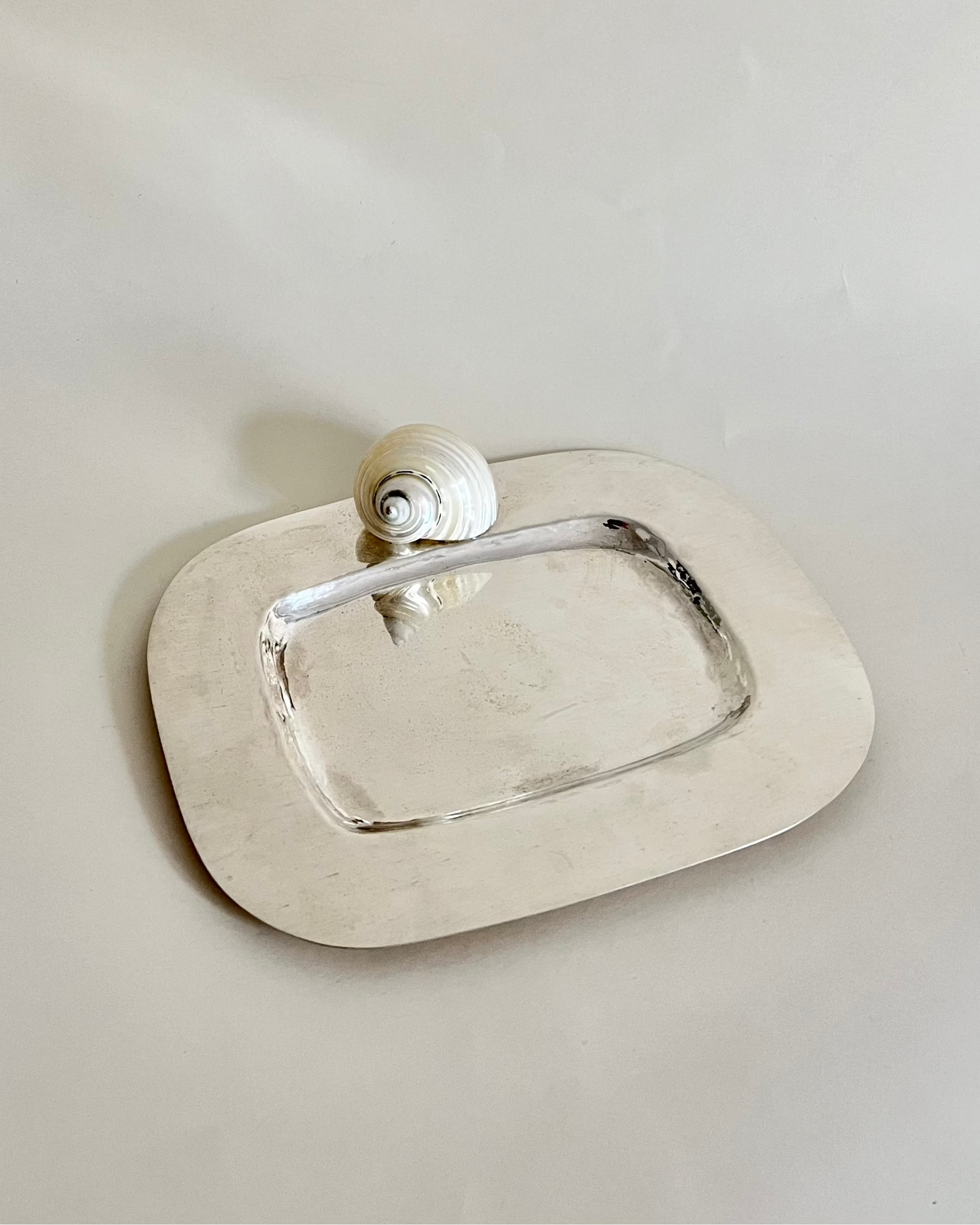 The Butter Dish 925 Silver Plate by Tavares 1922 is a rectangular silver tray with rounded edges, adorned with a white spiraled turbo shell at one corner, displayed against a plain light background.