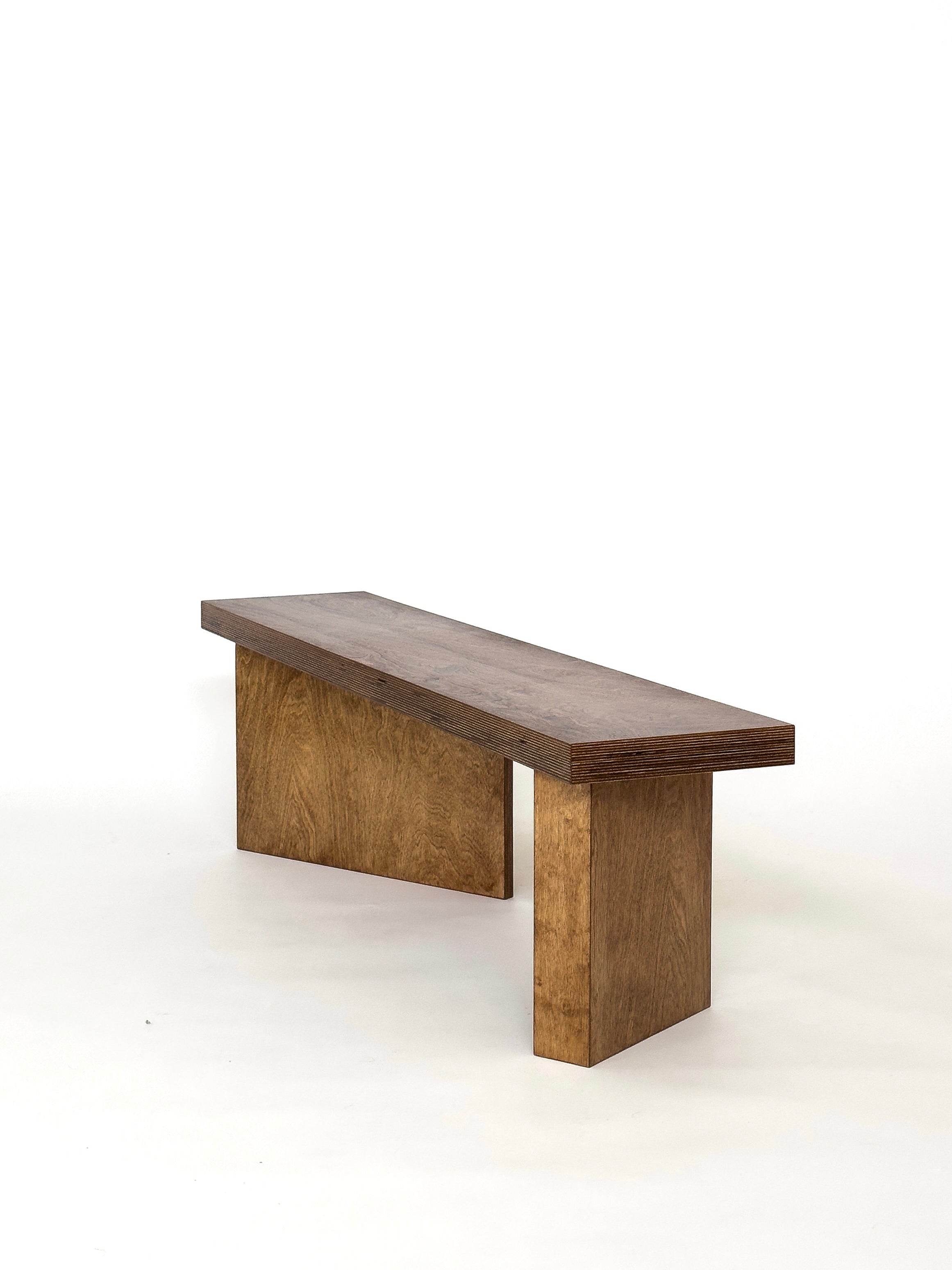 Introducing the Freeplan Bench by GOONS: a beautifully crafted wooden bench set against a white background, exemplifying superior craftsmanship. It boasts a flat rectangular seat and two sturdy rectangular legs, all finished in natural wood, highlighting expert artisanal skills.