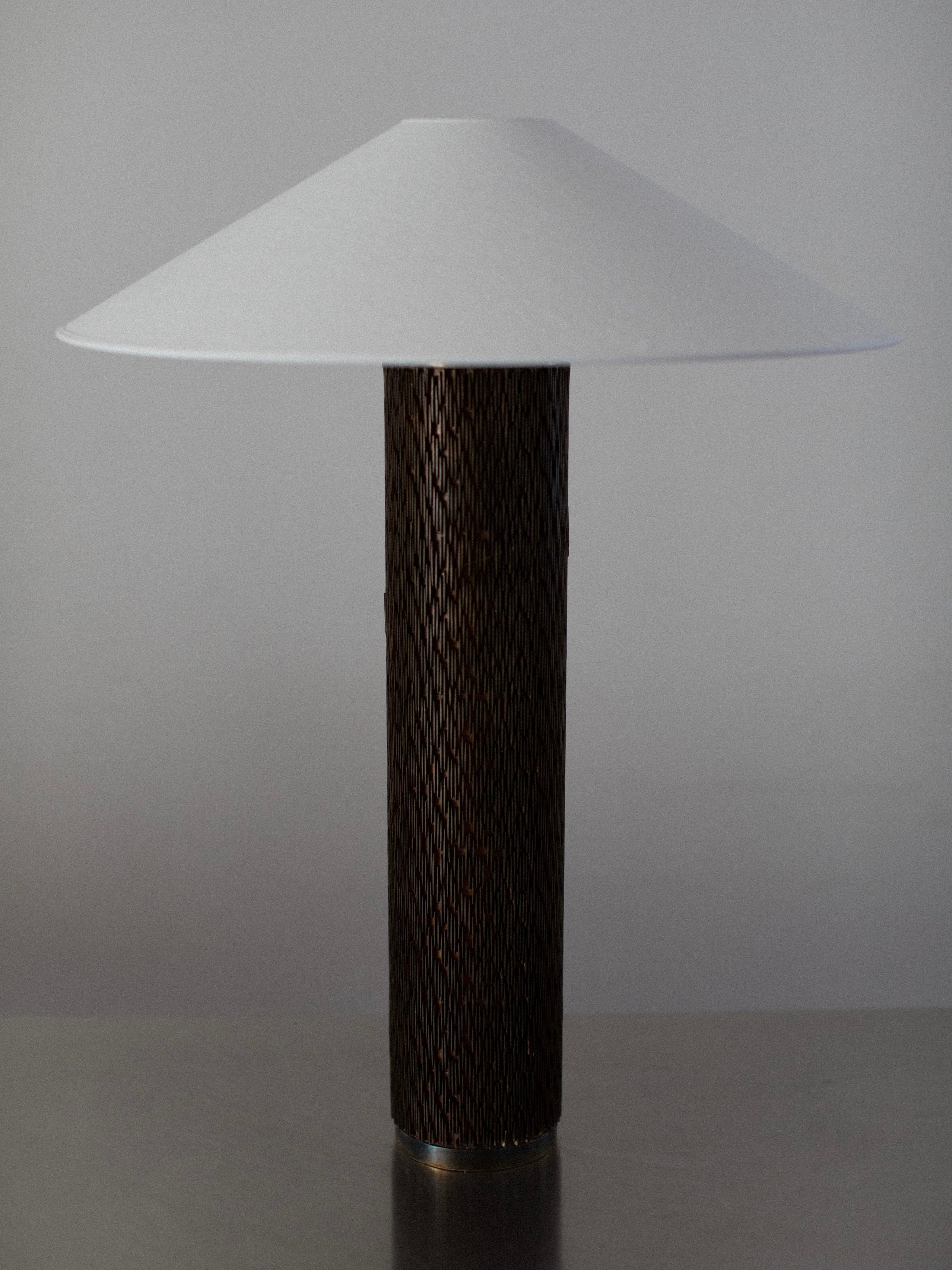 The Brutalist Floor Lamp by Out For Lunch features a sleek, modern design with a wide, white conical shade and a cylindrical wooden base. It is elegantly placed on a plain surface against a neutral background.