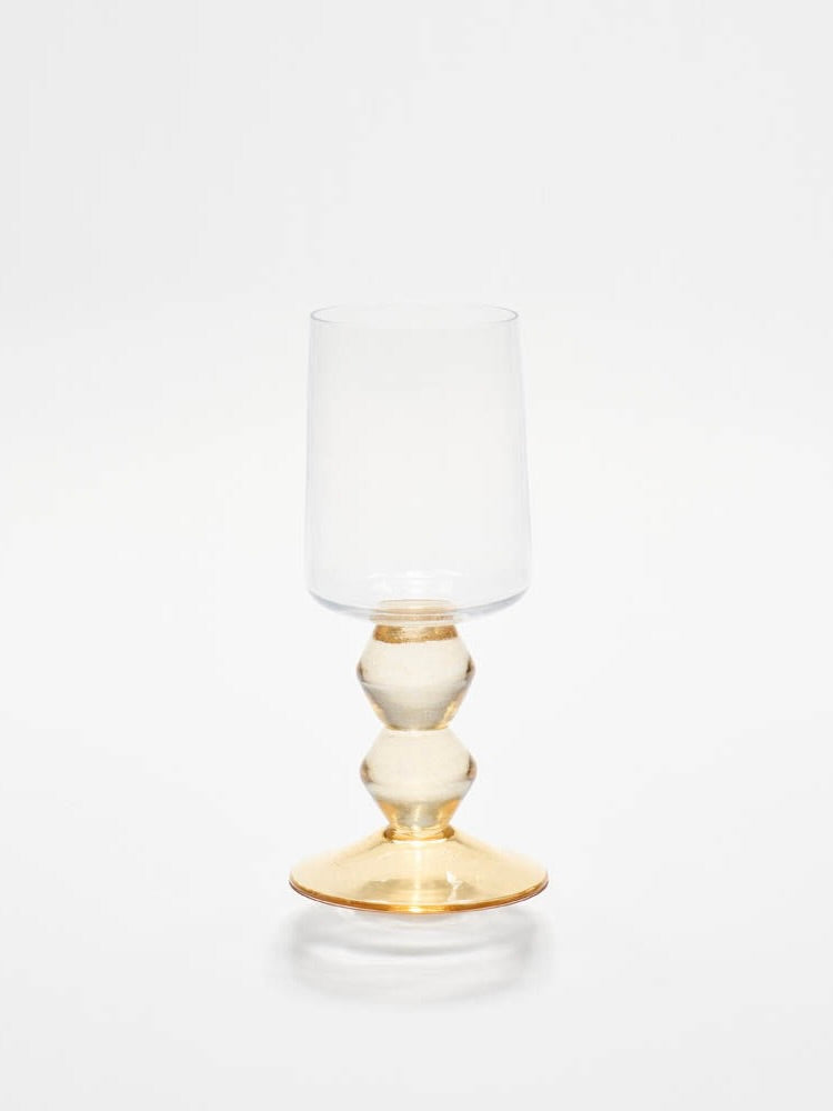 The New York Wine Glass in Whisky by Gather, showcasing a handmade spherical stem and gold base, is set against a white background.