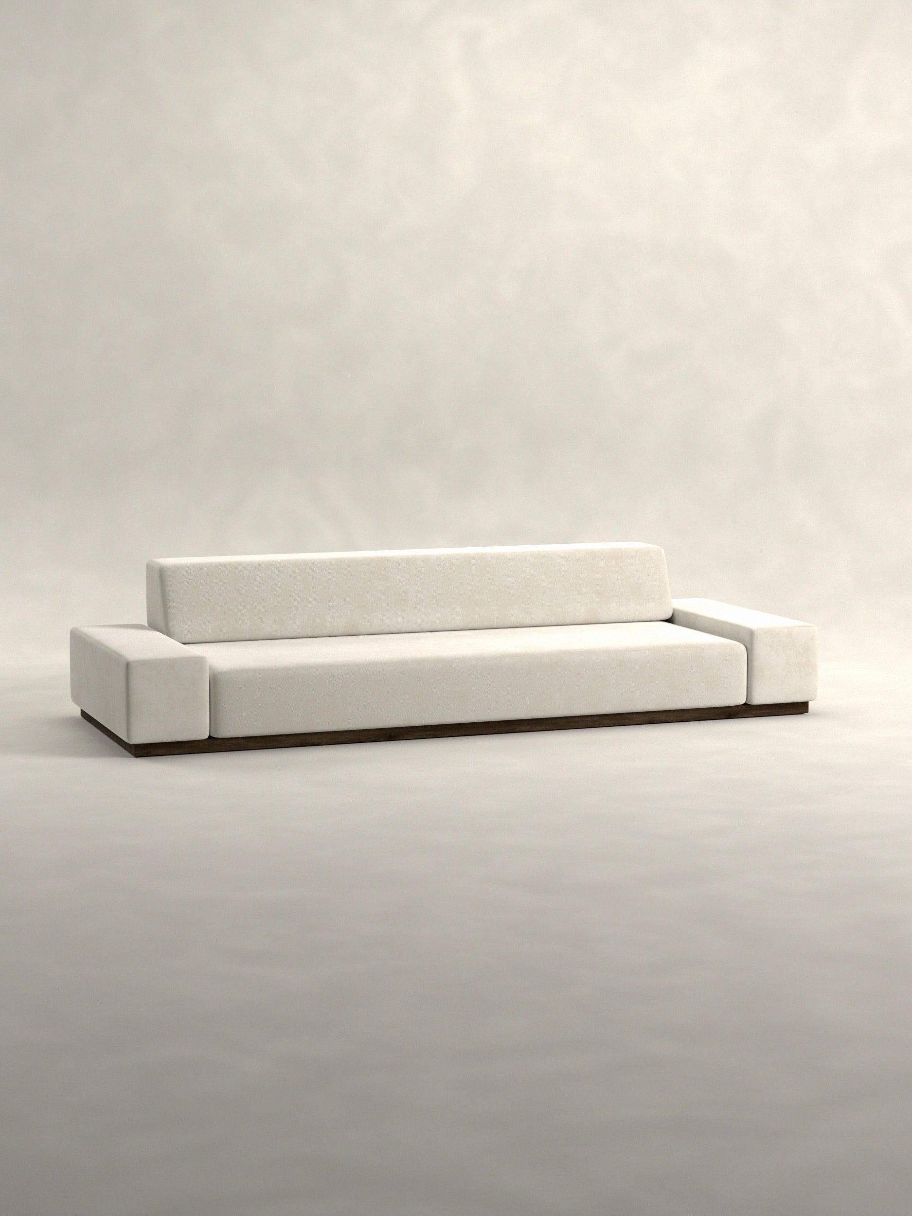 Siete Studio's 'Nube' Sofa is a minimalist masterpiece with clean lines, featuring light gray upholstery, a low rectangular backrest, and wide armrests. Its sleek design sits on a solid walnut base inspired by 70s Italian aesthetics.