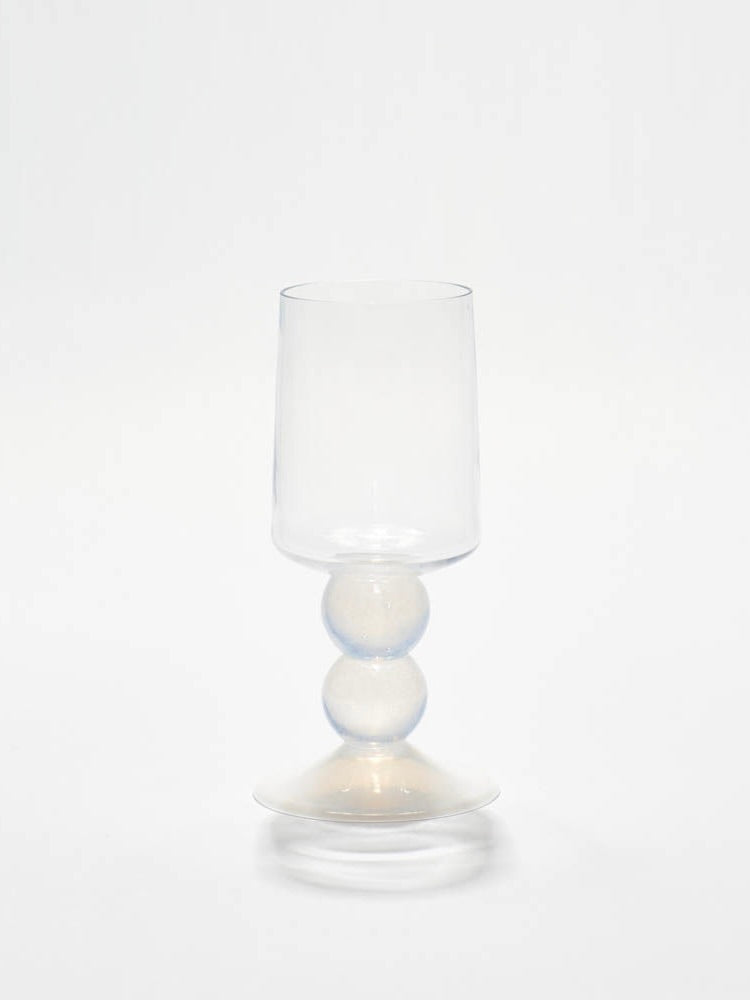 The New York Wine Glass in White by Gather features a clear glass goblet with an opulent design, showcasing two unique round spheres in the stem against a plain white background.