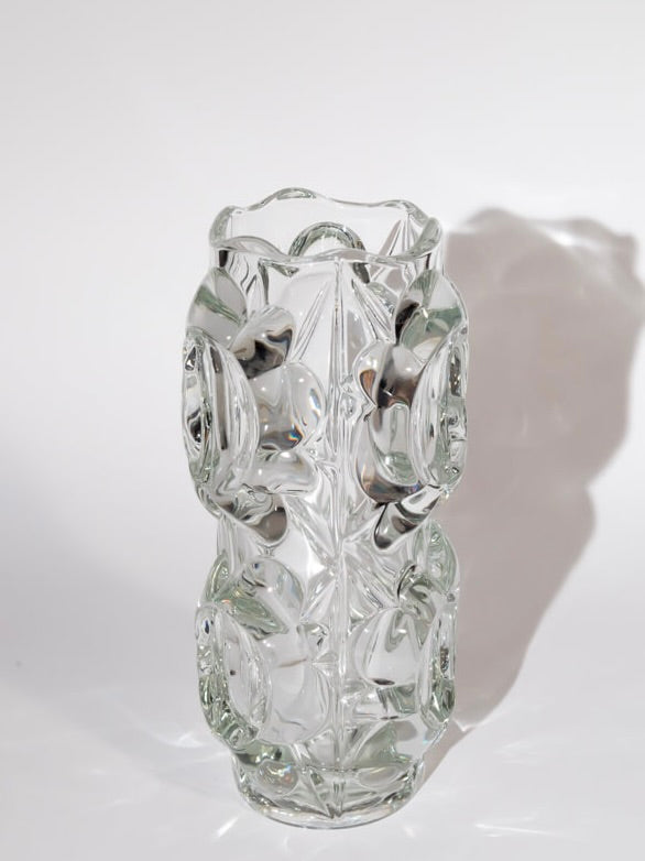 The Break The Mould Magasin offers a tall, transparent glass vase by Frantisek Peceny for Hermanova Hut, featuring intricate abstract patterns that form an irregular surface. Showcasing mid-century craftsmanship, it exudes minimalist elegance and casts a soft shadow on a plain white background.