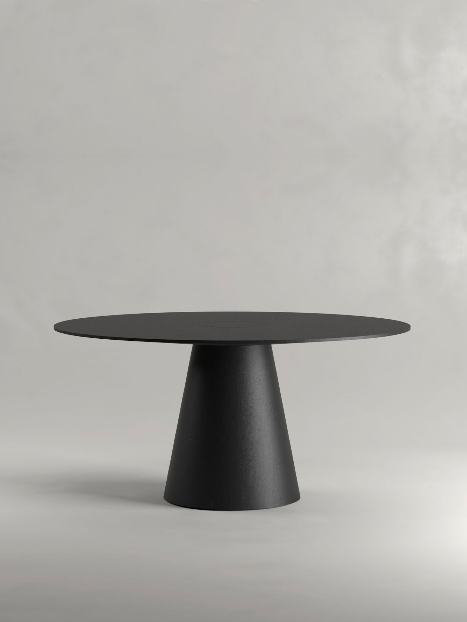 The 'Totem' Dining Table by Siete Studio is a modern, minimalist round black piece with a conical pedestal base made from solid walnut, elegantly set against a plain light gray background.