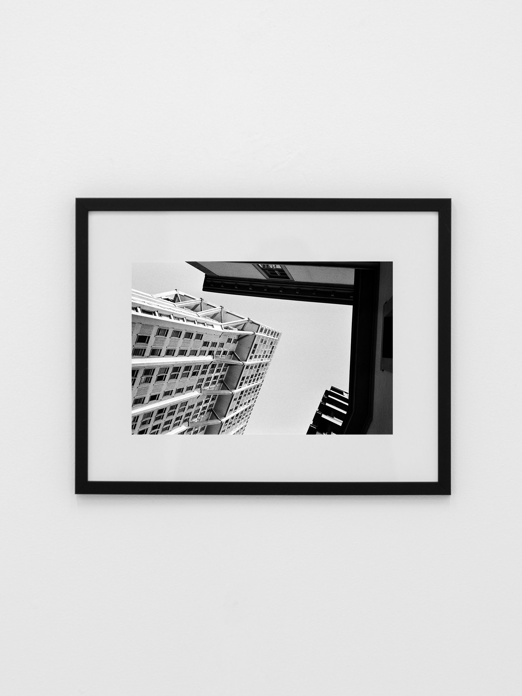 'Memory #09' Photography by COSEINCORSO: A black and white modern building photo, low-angle shot, limited edition print in a simple black frame, displayed on a plain white wall.