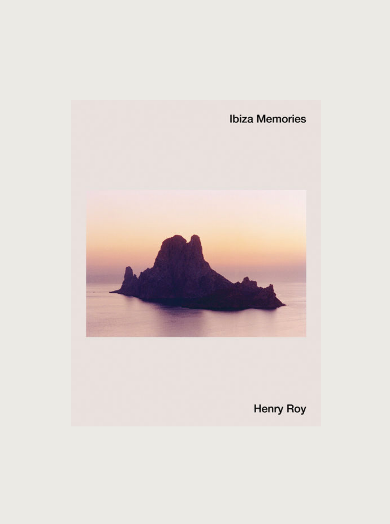 The cover of the book "Ibiza Memories by Henry Roy" by Maison Plage captures a serene photography experience with an image of an island rock formation at sunset, surrounded by calm sea waters. The sky displays soft pink and orange hues, while text with the title and author's name flanks the image on a beige background.
