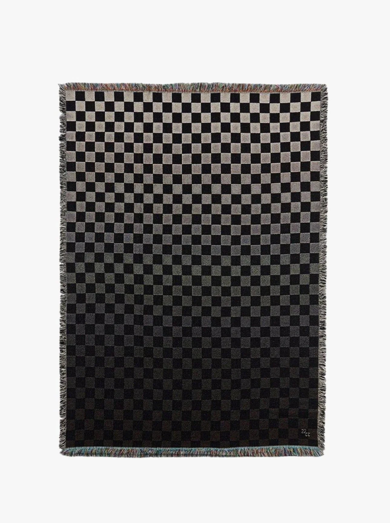 The Iki Cotton Jacquard Throw by 2222Studio features a black and gray checkerboard pattern with small gradient squares fading from light to dark, finished with fringed edges.