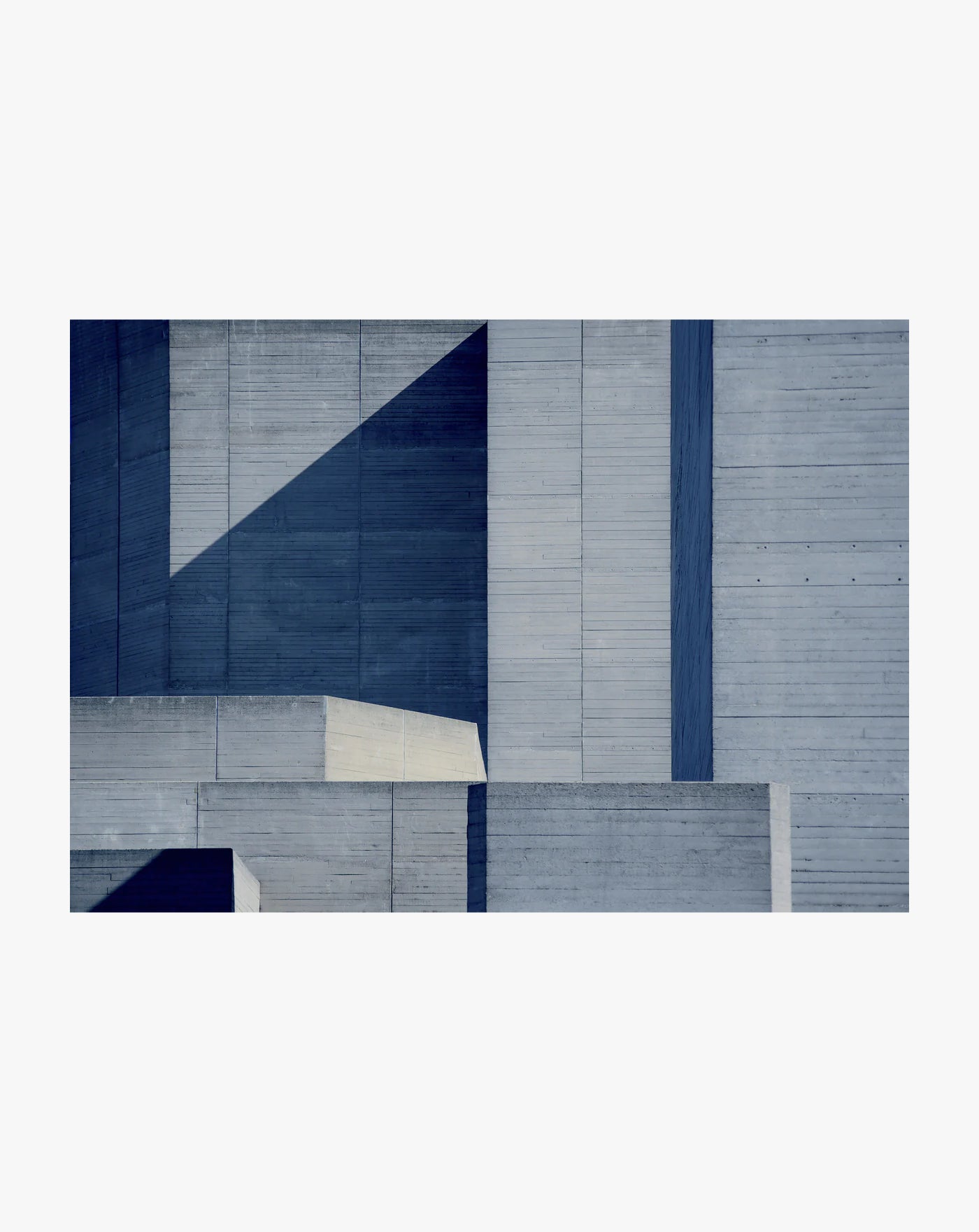 Amelia Lancaster's "Beautiful Brutalism (National Theatre XII)" features an abstract composition of geometric shapes and planes in blue and gray. Sharp angles and shadows enhance its contemporary, minimalist design, adding depth and dimension.