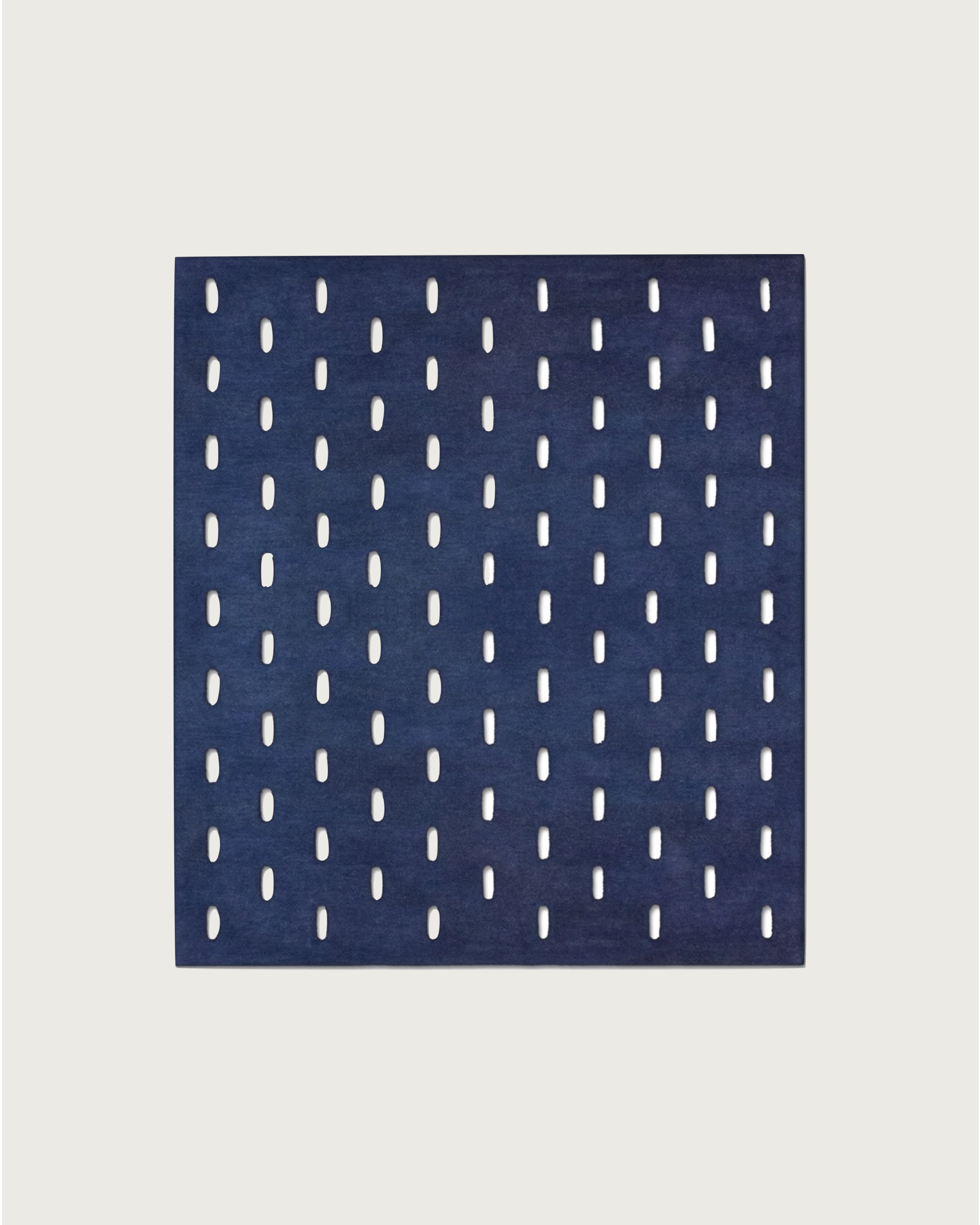 The GRATA BLU rug by Hafner Büro features a square marine blue design with vertical oval cutouts in a grid pattern on a light background.