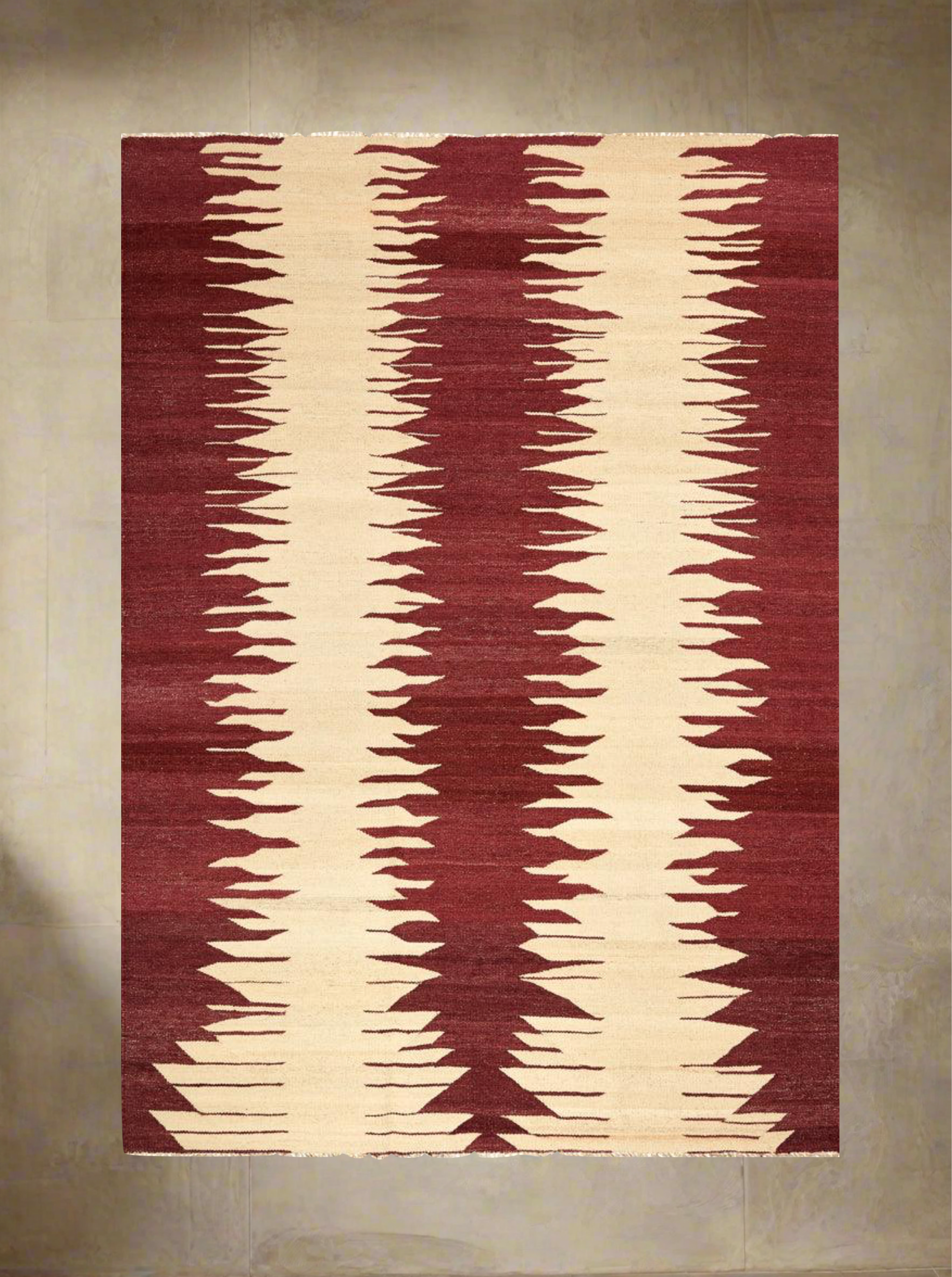 The ISHKAR Waves Kilim features jagged, vertical stripes in alternating colors of dark red and beige. Handwoven from raw wool kilim, the background is a neutral beige, contrasting with the vivid design of natural dyes.