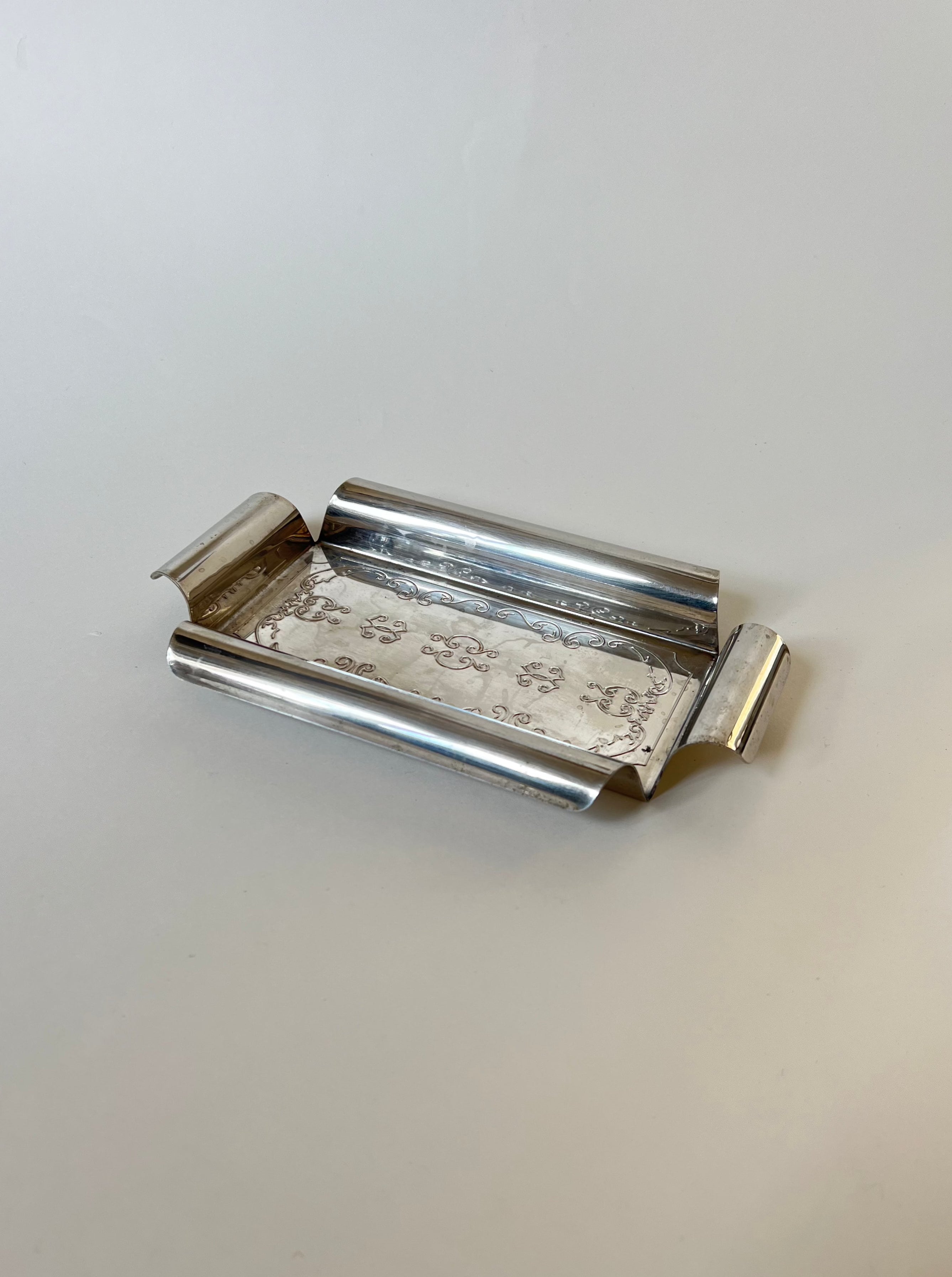 Decorative silver butter dish with intricate floral patterns and elegant design