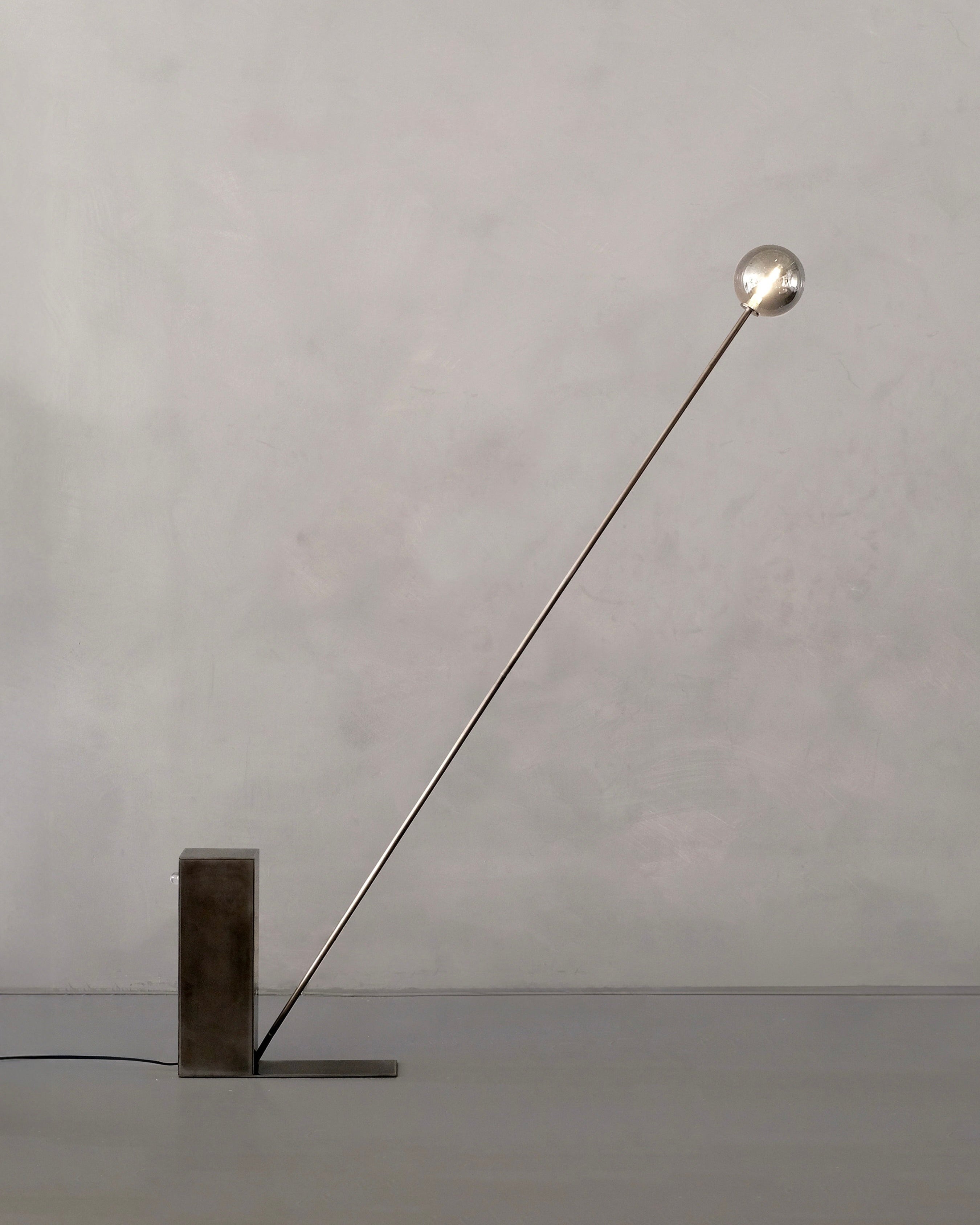 Oblique Glow floor lamp with angled brass arm and sphere bulb