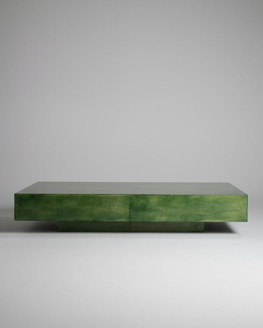 The Green Parchment Table by Galerie Vauvart, a low rectangular Italian coffee table in Aldo Tura style, features glossy green parchment wrapping, a minimalist design, and smooth finish. It sits on a beige carpet against a cream paneled wall.