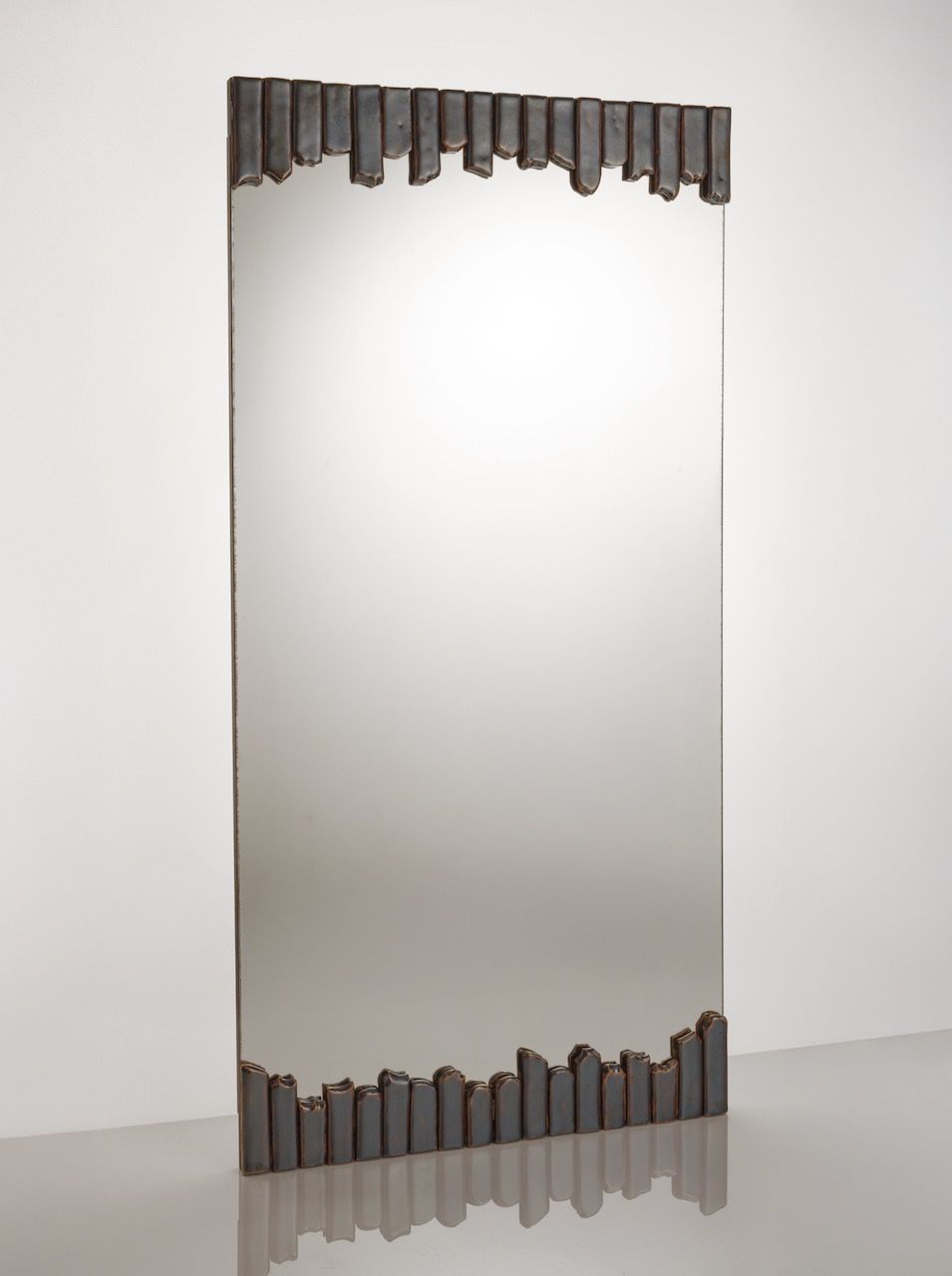 The Cliff Collection Contemporary Mirror by Katia Langeard features a plain reflective surface and a decorative border of irregular dark metallic bars on the top and bottom, standing tall to bring modern elegance to any space.