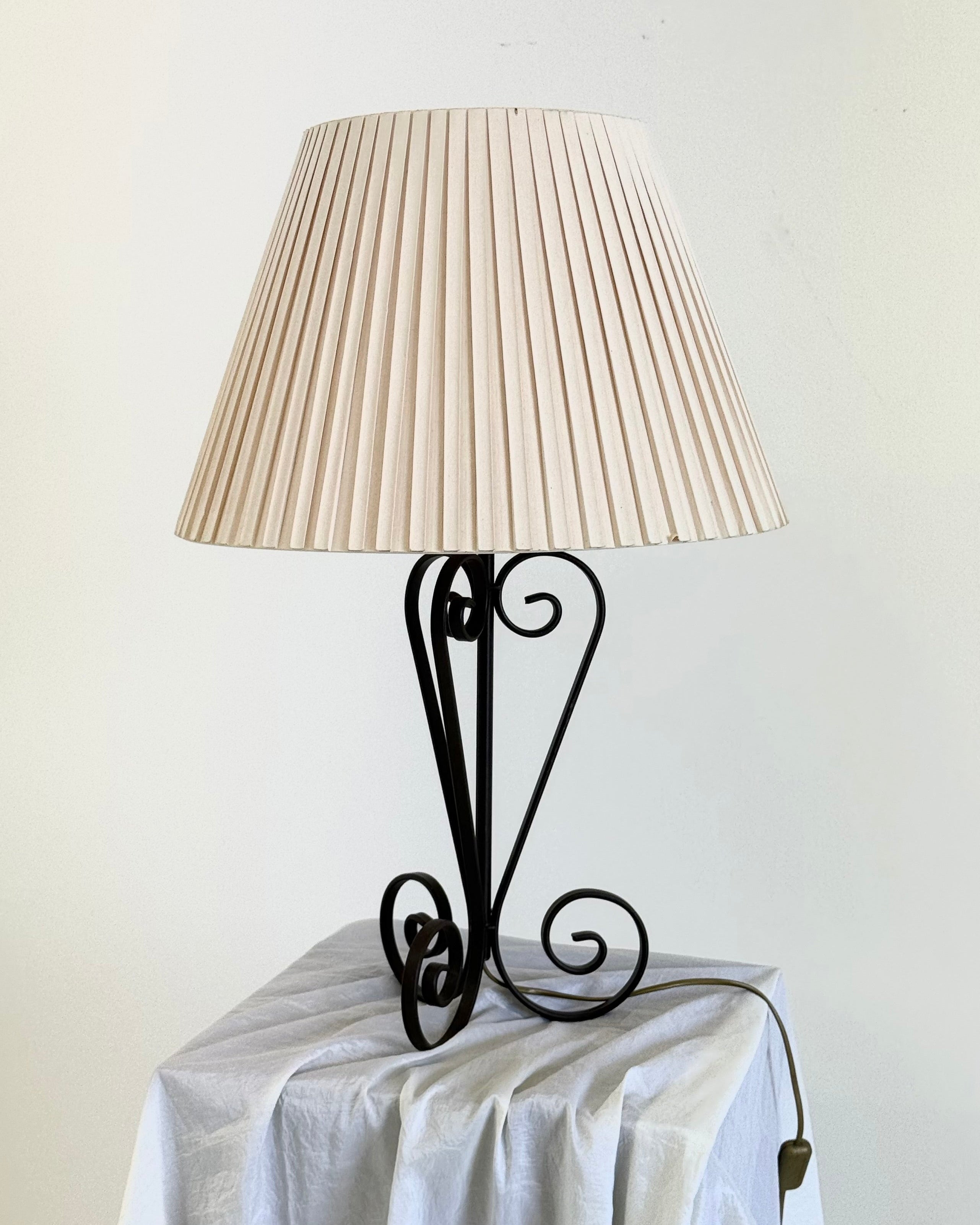 Vintage wrought iron table lamp in a swirl shape with a pleated shade — detail view