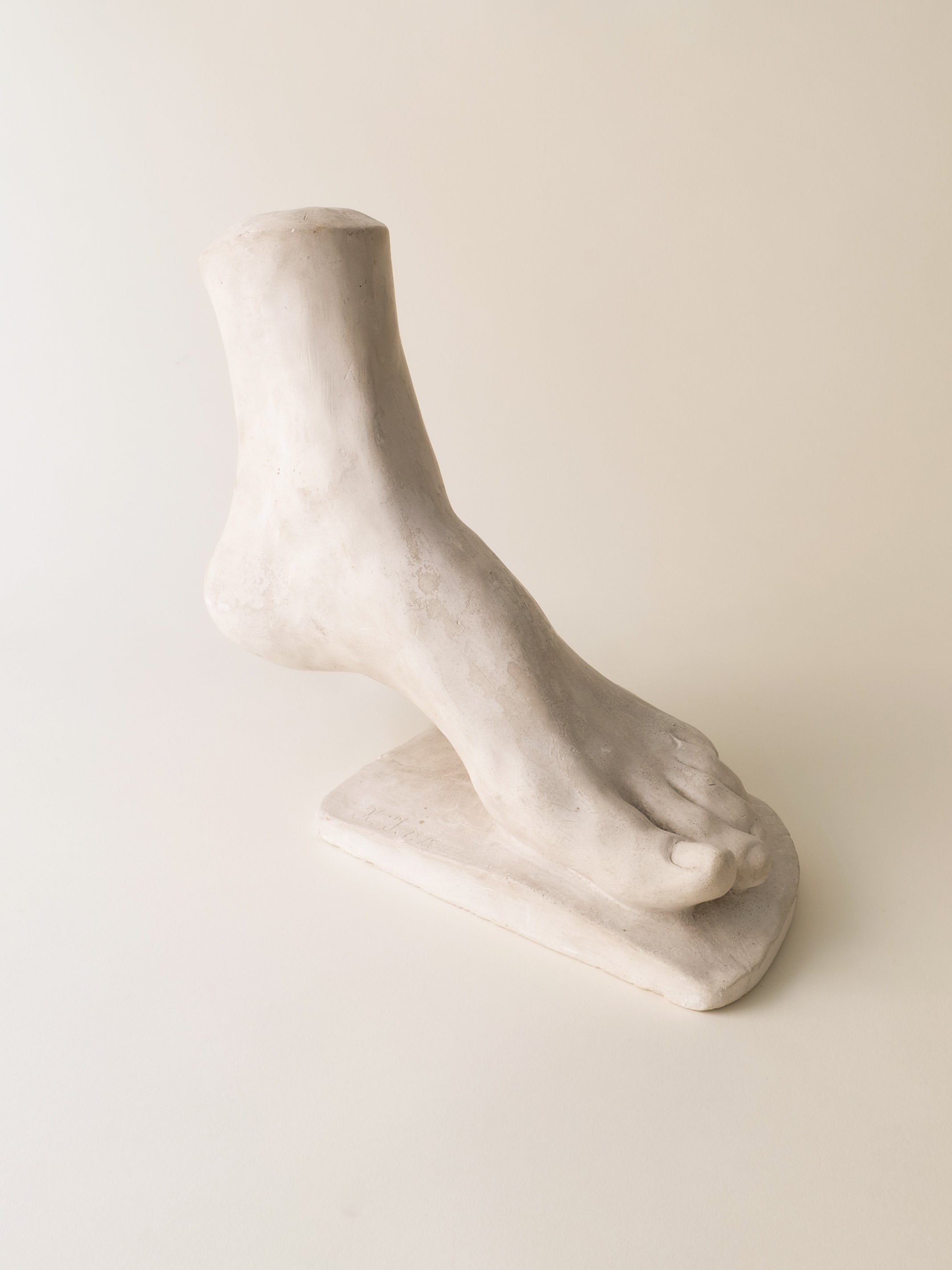 White marble anatomical foot sculpture on neutral background