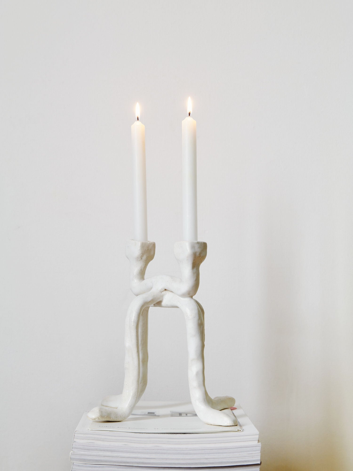 White ceramic human figure candleholder with two lit candles