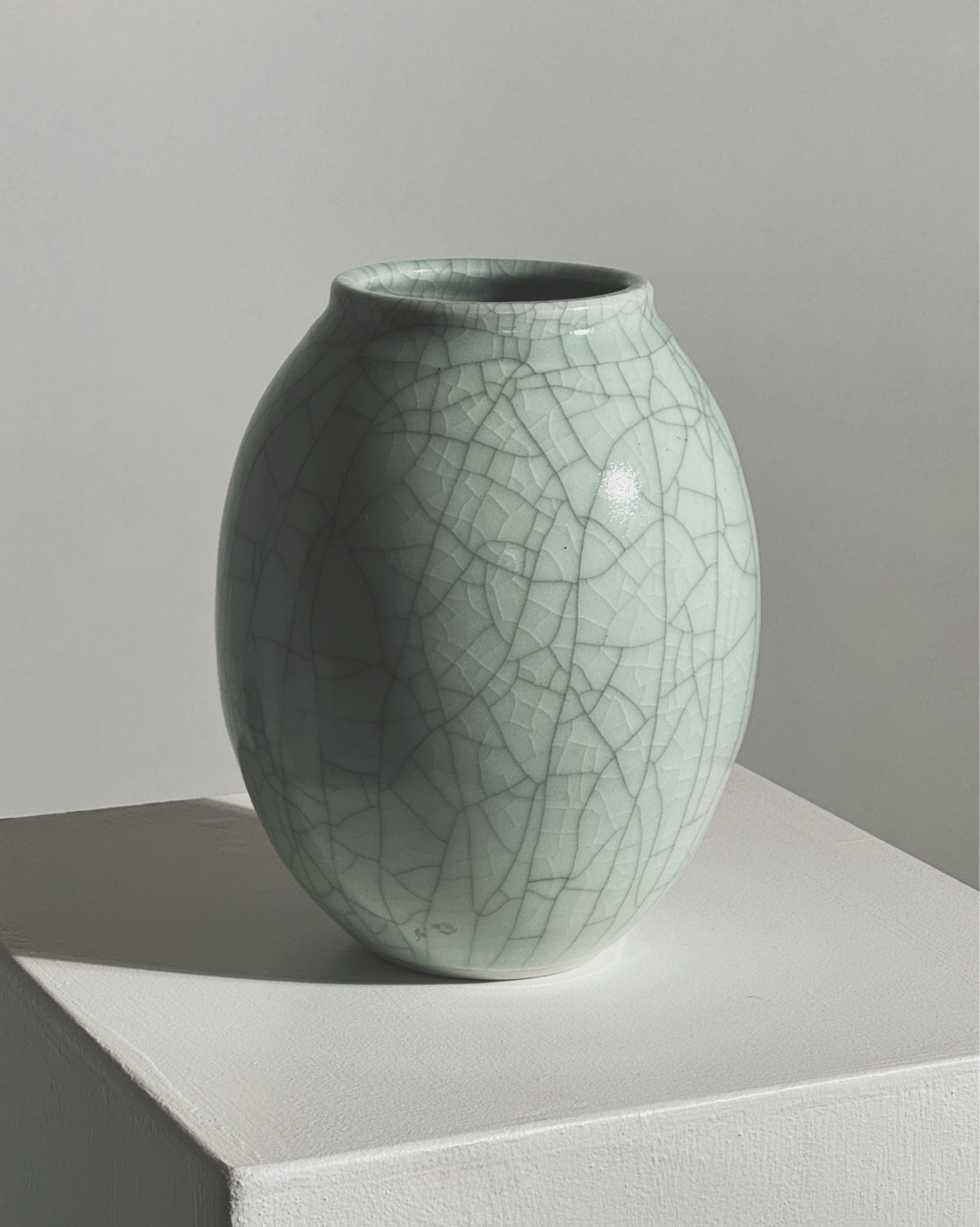 Celadon crackle-glazed ceramic vase with organic oval form