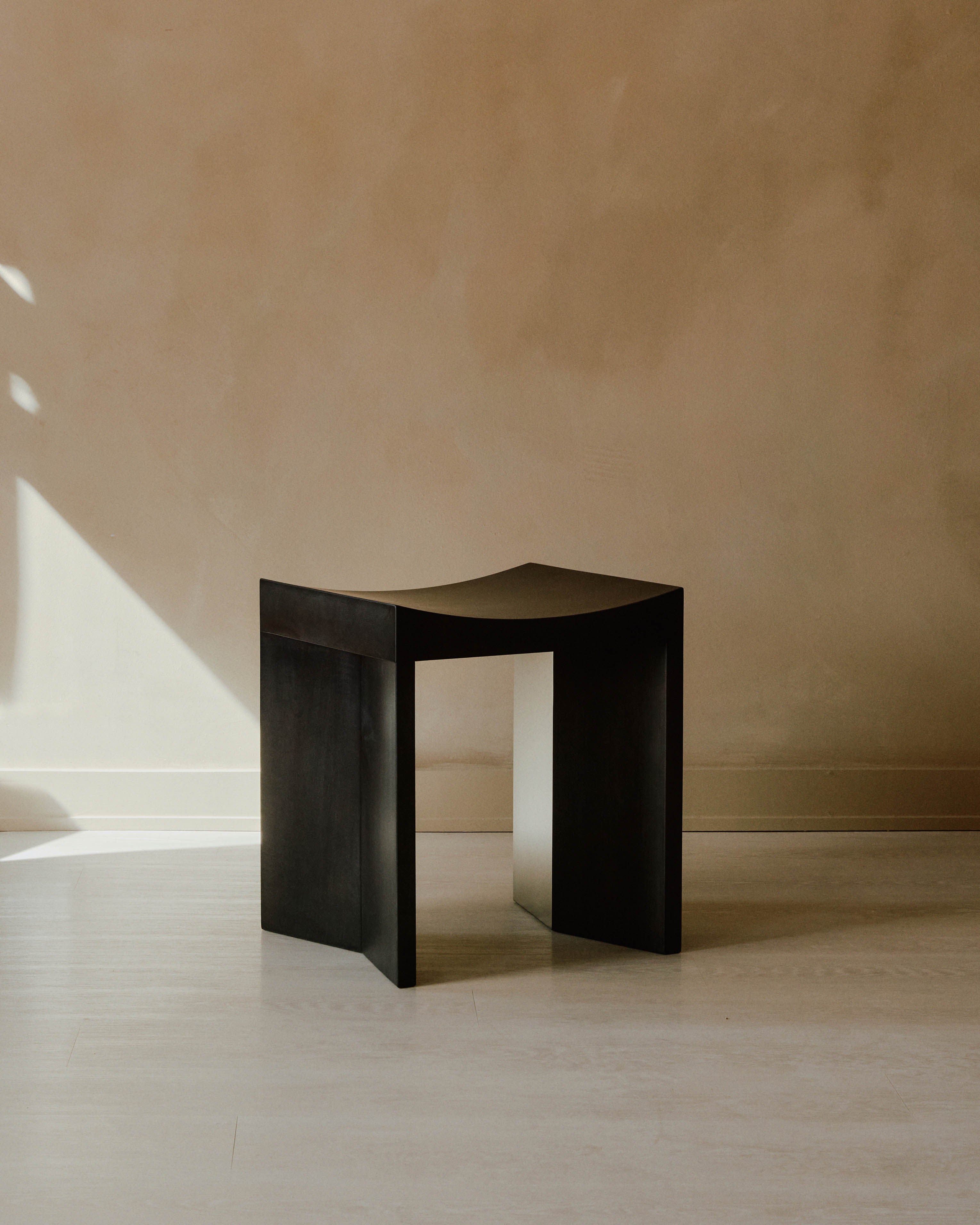 Arc Stool — side angle showing dark wood finish in minimalist setting