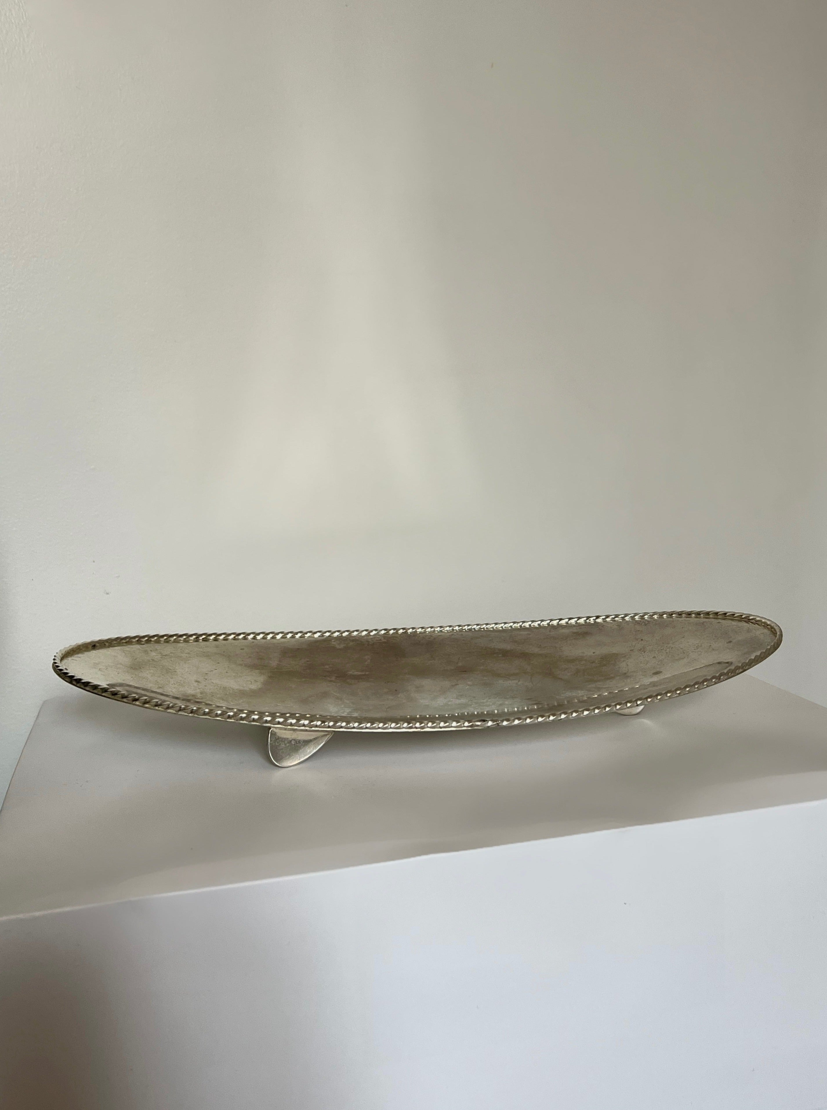 Long silver serving dish with intricate floral design and elegant handles