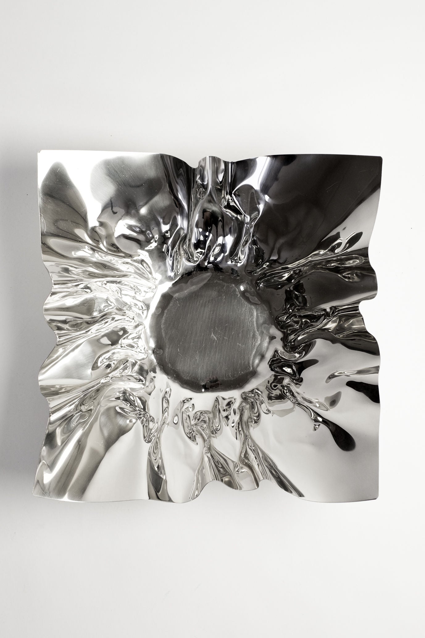 The Extra Large Folded Chrome Bowl by septembre studios features wavy, crumpled edges and a smooth, reflective center—photographed from above on a white background—ideal for adding character to your space.