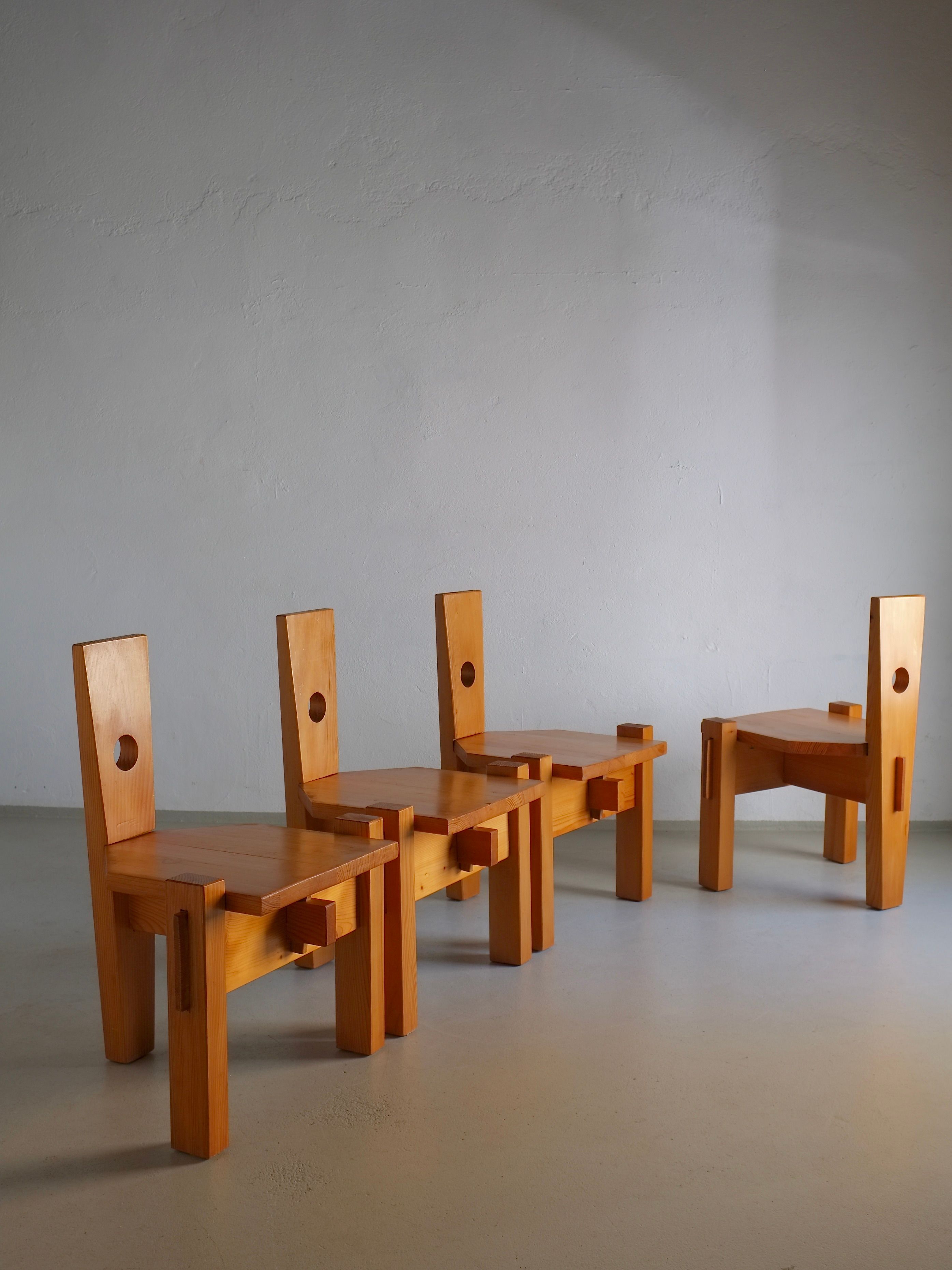 Four Sculptural Pine Chairs by Erwin Egel from the 1960s, offered by Veter Vintage, featuring geometric designs and circular cutouts in the backrests, are arranged in a well-lit room with a smooth, light-colored floor and a plain gray wall.