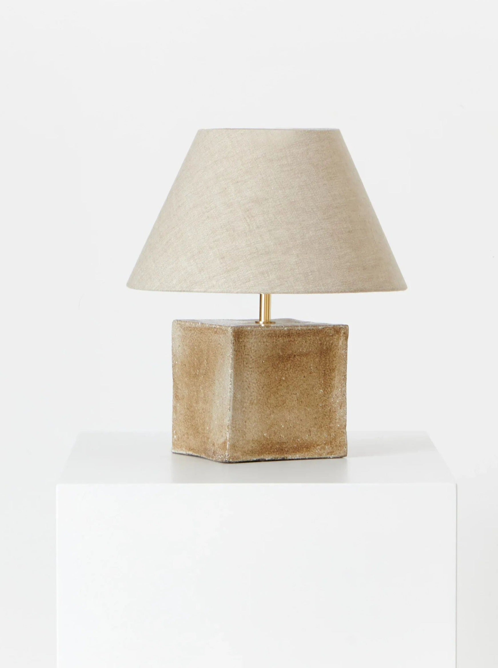 The Arouca Table Light Brown Sugar by Project 213A features a handmade beige, square ceramic base and matching fabric shade, crafted in Northern Portugal and shown on a white pedestal against a plain white background.
