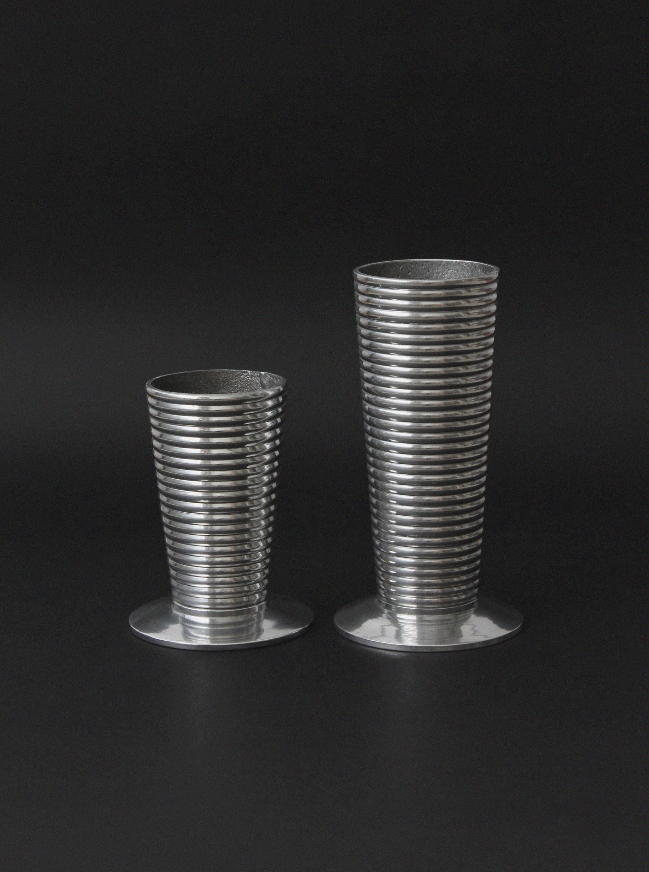 Two ribbed aluminum vases in different heights on dark background