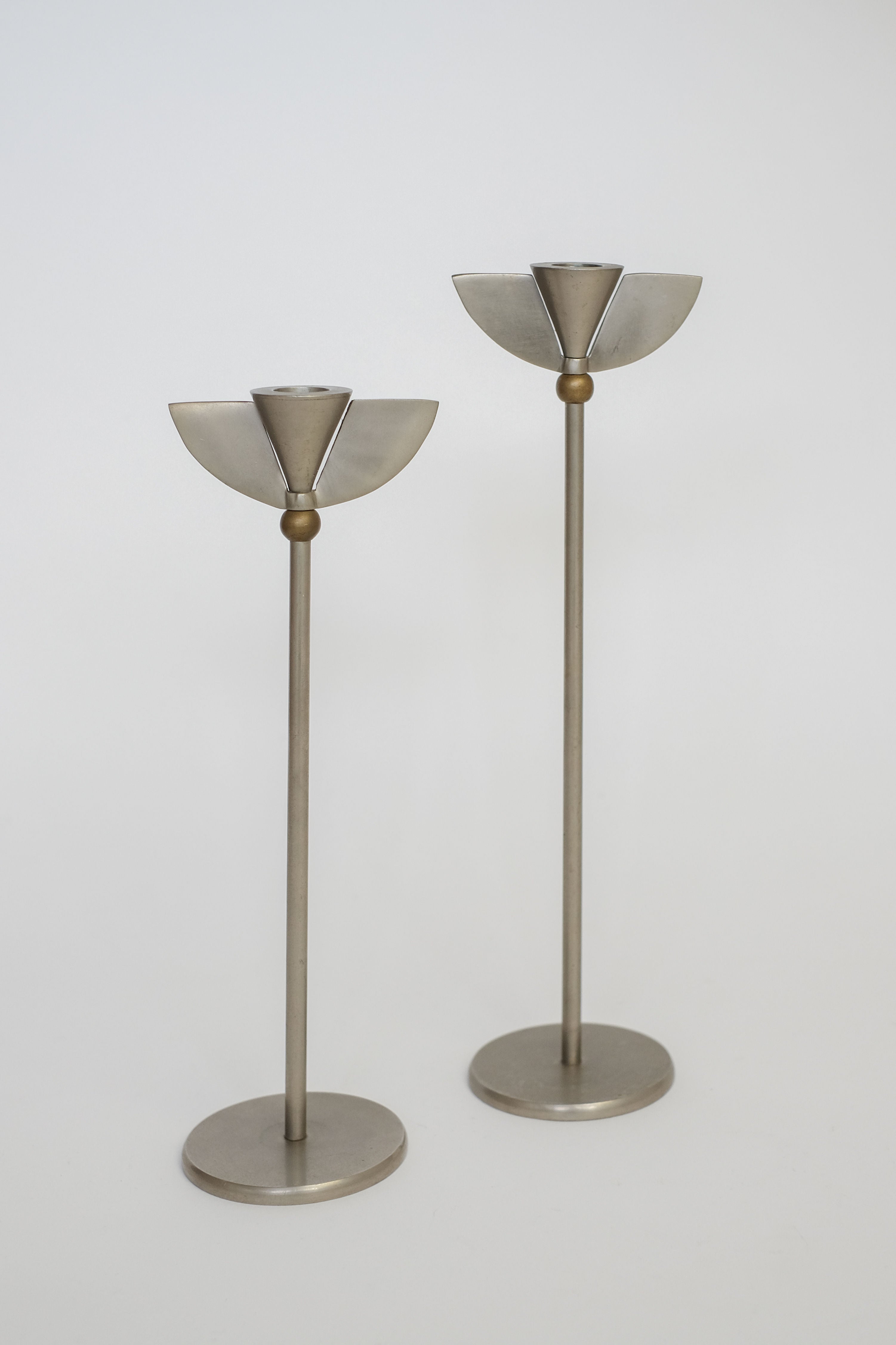 Set of 2 Memphis Candleholders by septembre studios featuring modern, minimalist metallic design with tall, slim stems, round bases, and semicircular holders inspired by Memphis Milano style. Shown on a plain white background.
