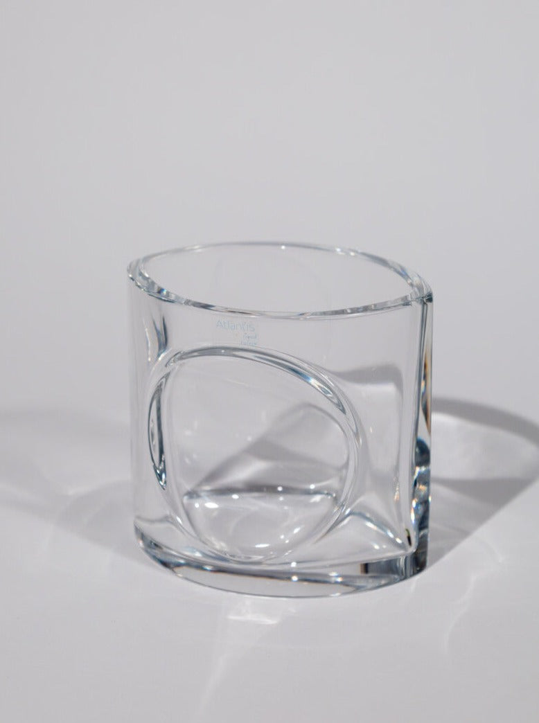 A Rare Portuguese vintage crystal pen holder from the Break The Mould Magasin Atlantis Portugal collection with a thick base and cylindrical body. The pen holder features a unique indented design on one side, creating a visual ripple effect. The background is a plain, light gray.
