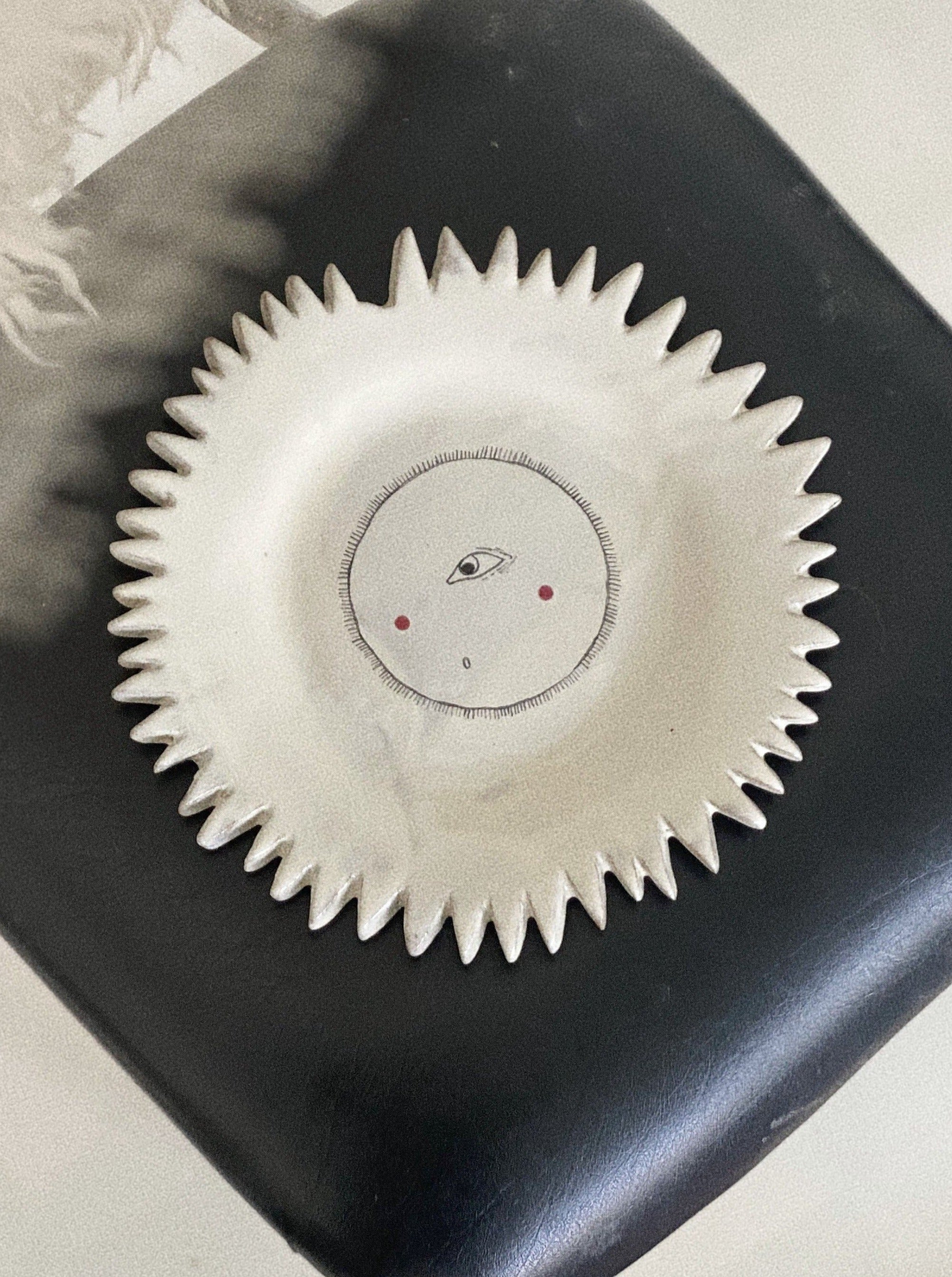 A close-up image of a round, yellow Sun Plate with intricate floral patterns