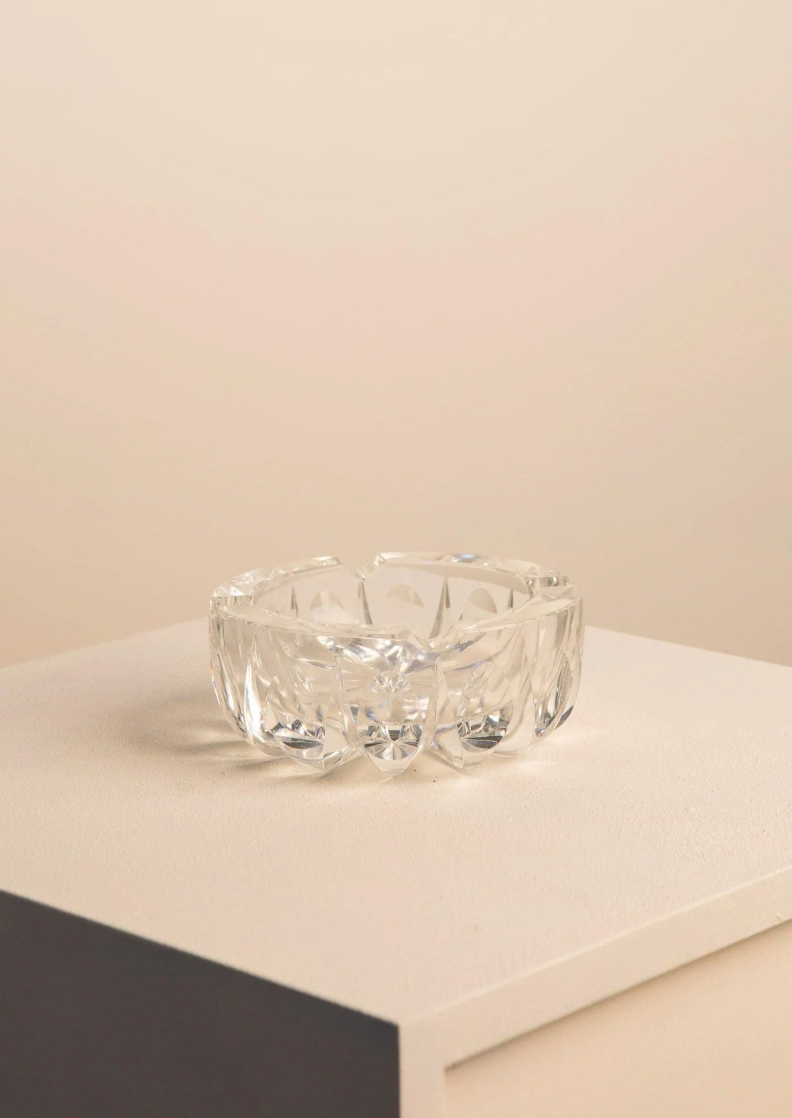 A Treaptyque Murano Bowl by Flavio Poli for Seguso with a diamond pattern, placed on a beige surface with a partial view of a dark gray block in the foreground, against a light beige background.