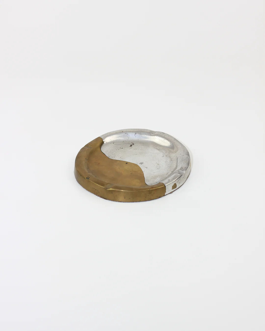 The Boga Avante Shop presents the Brutalist Ashtray, designed in aluminum and brass with a simple two-tone look. Set against a plain white background, this modern piece beautifully showcases its unique material blend.