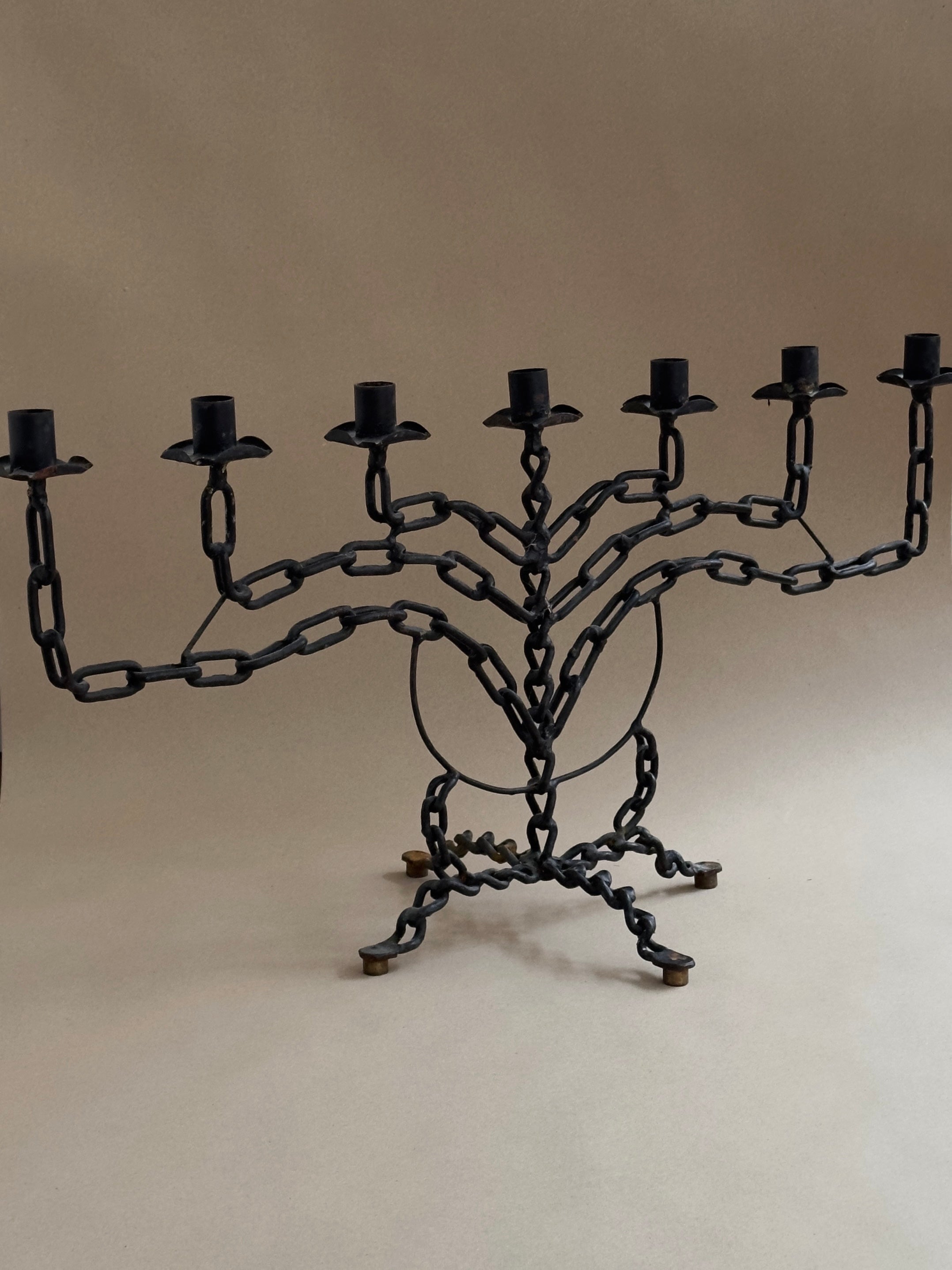 The Galerie Storm Brutalist Candleholder is an eight-branch black metal piece with chain link design and twisted details, showcasing bold artistry and brutalist style against a neutral background.