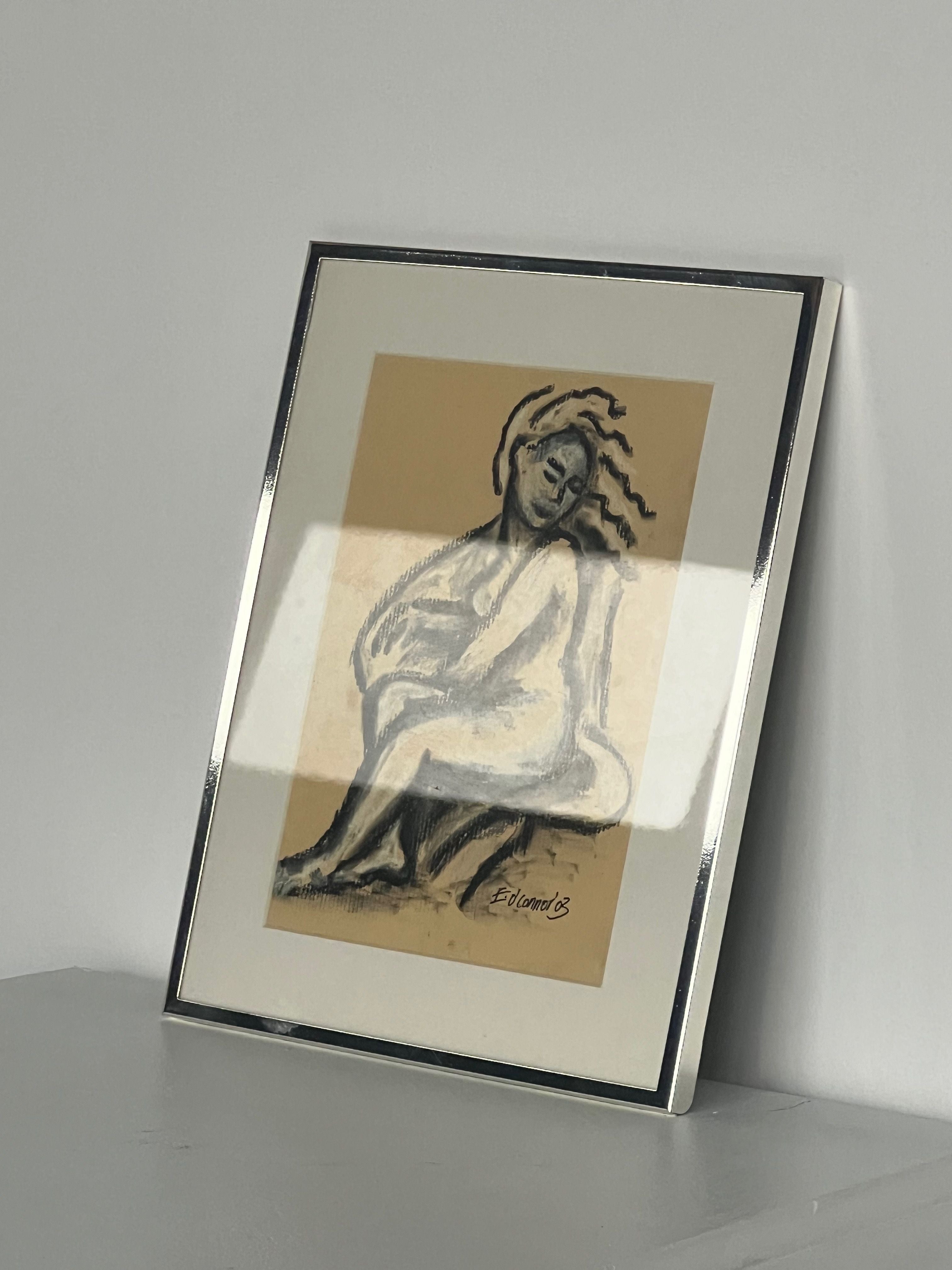 The "Pastel Drawing" by E.D. Connor from Porter Studio features a stylized seated figure, with abstract lines indicating movement. It sits against a neutral beige background, encased in a polished chrome frame and displayed on a smooth surface against a plain wall.